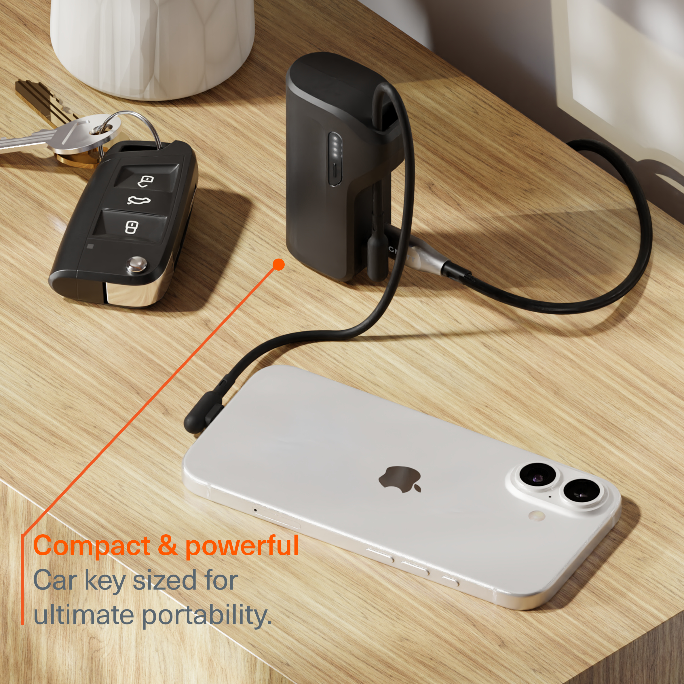 Un étui de chargement noir charge un smartphone blanc sur une table en bois.