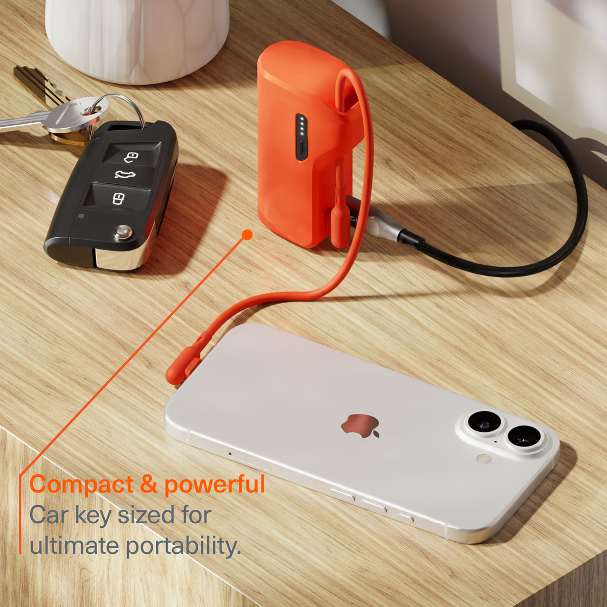 Ein orangefarbener Akku lädt ein weißes Smartphone auf einem Holztisch.