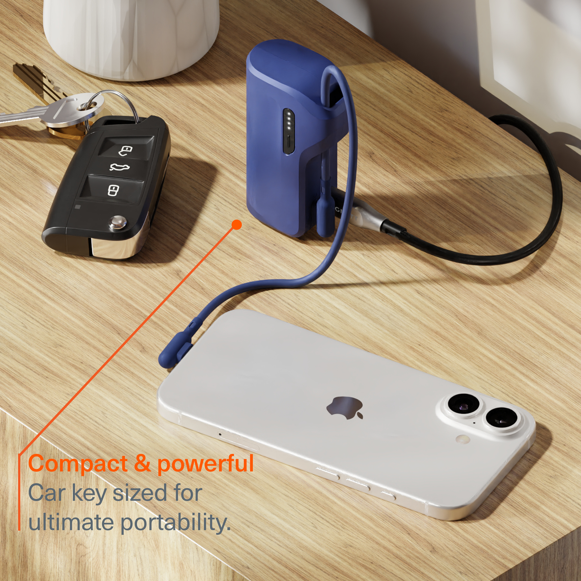 Un power bank blu, chiavi dell'auto e uno smartphone su una superficie di legno.
