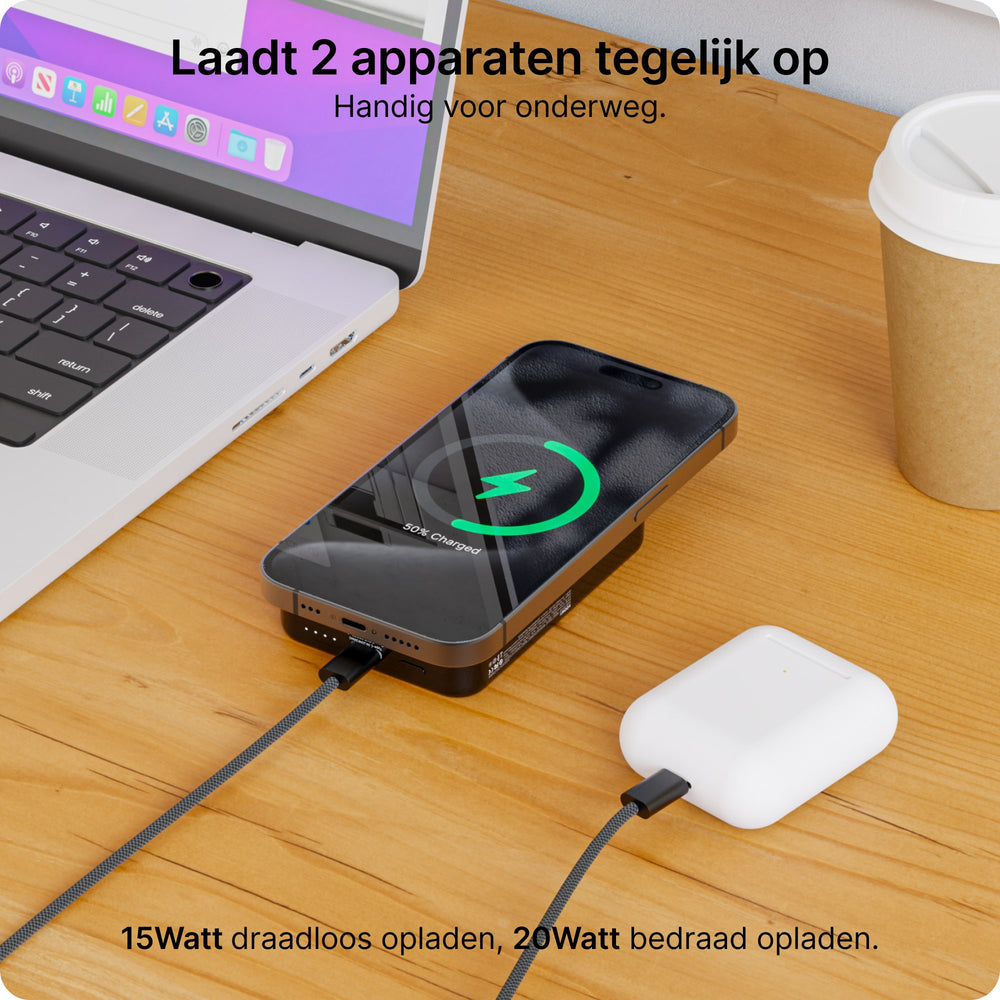 Un laptop, uno smartphone e auricolari si caricano su una scrivania di legno.