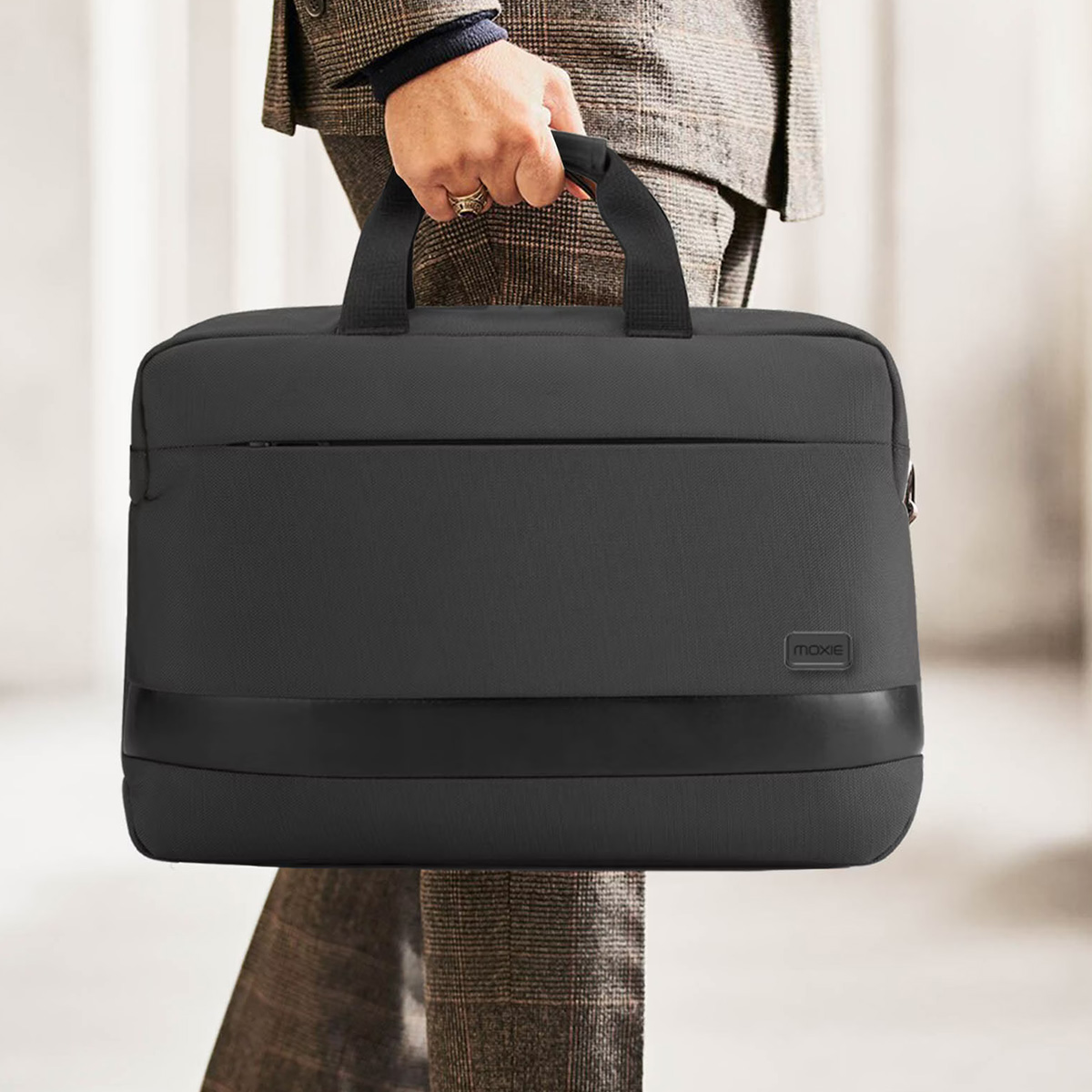 Eine Person im Anzug trägt eine schwarze Laptoptasche.
