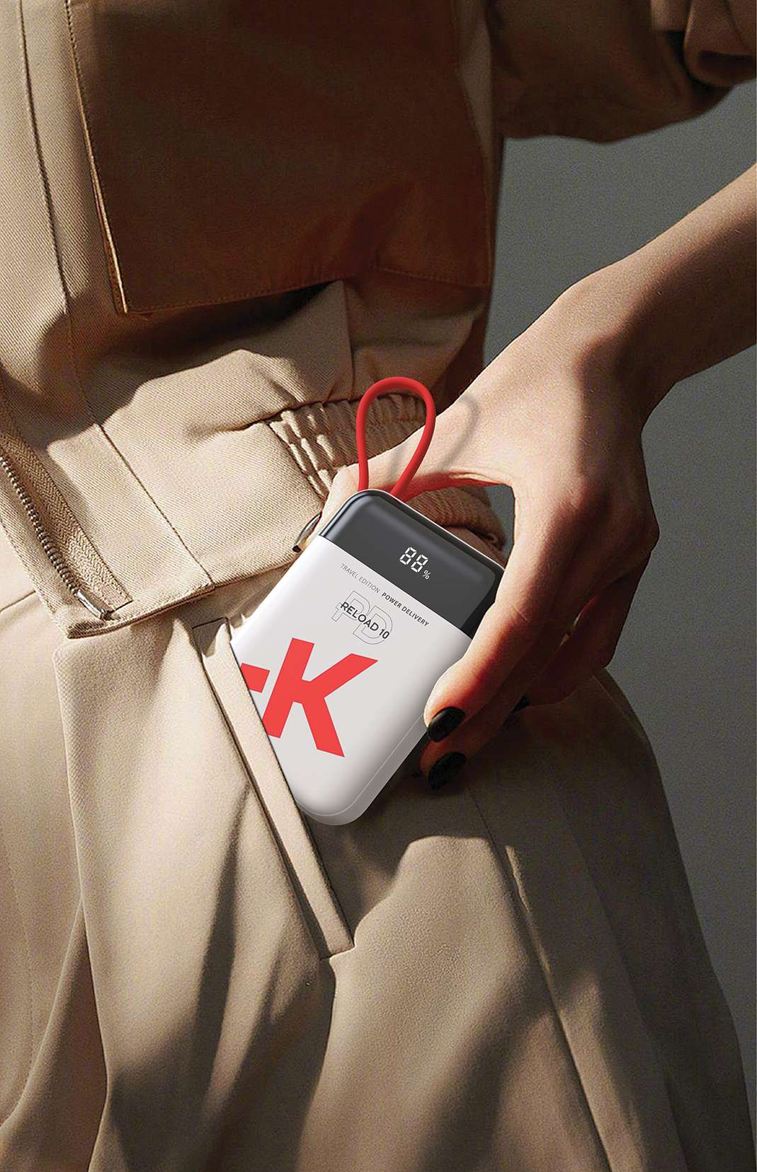 Une main tient une batterie externe blanche avec logo K rouge et affichage 88%.
