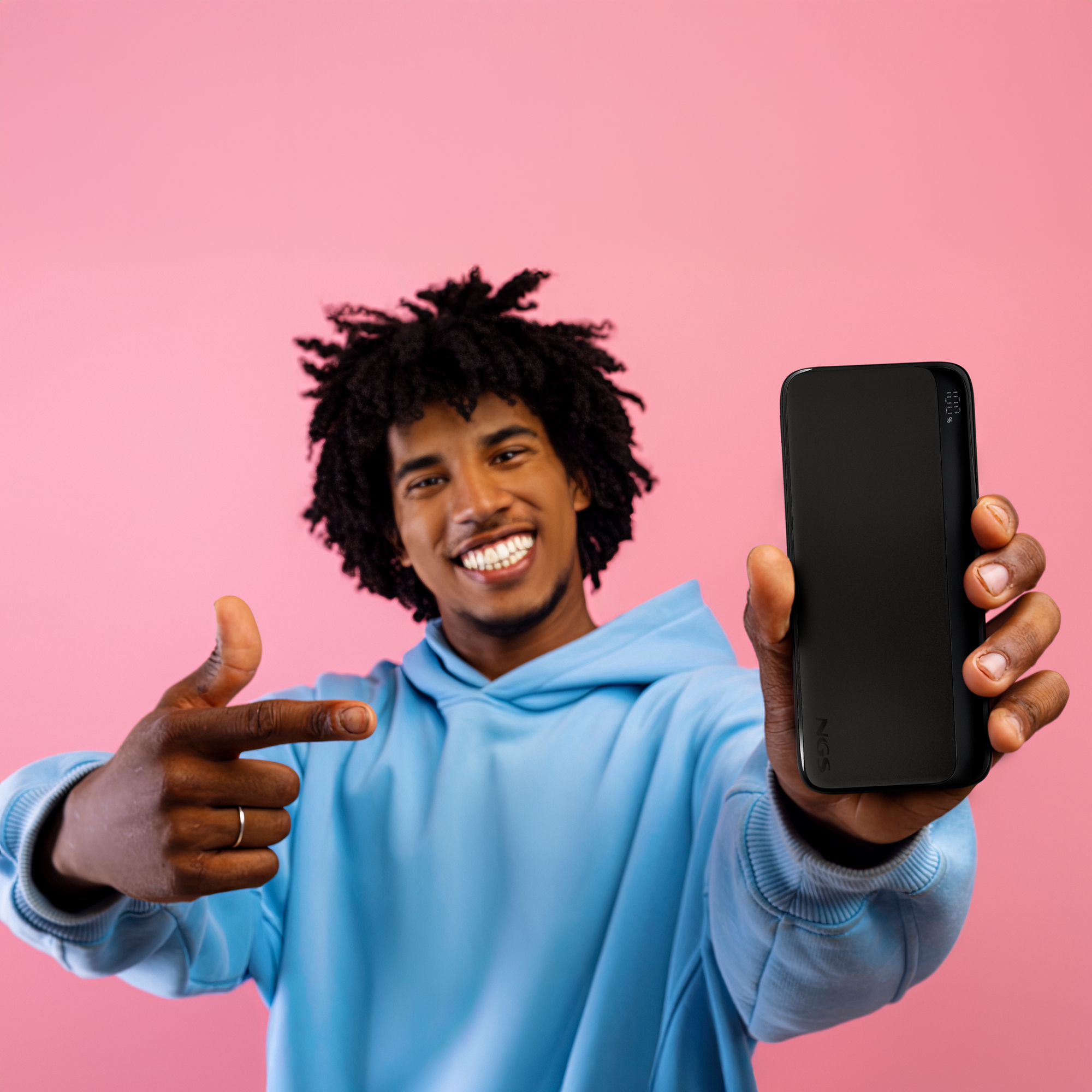 Un hombre con rastas y sudadera azul sostiene un power bank negro.
