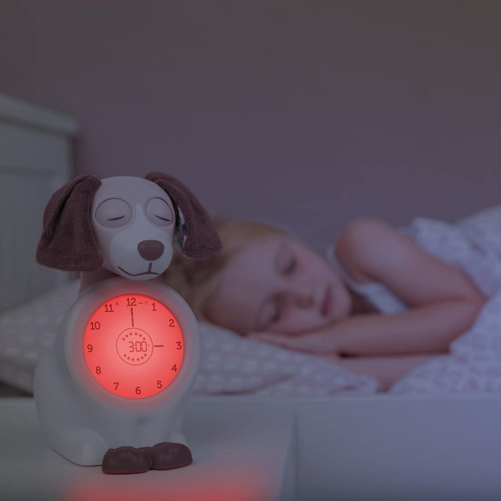 Luce notturna a forma di cane con quadrante luminoso, bambino dorme nel letto.