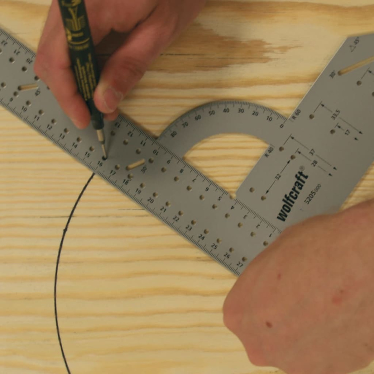 Mani usano uno strumento di tracciamento su un righello ad angolo metallico per disegnare una curva su legno.