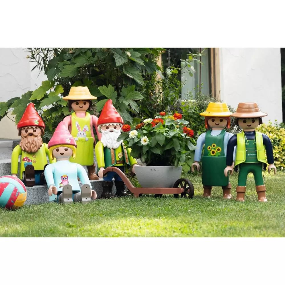 Gartenzwerge und Figuren stehen im Gras vor einem Haus mit Blumen.