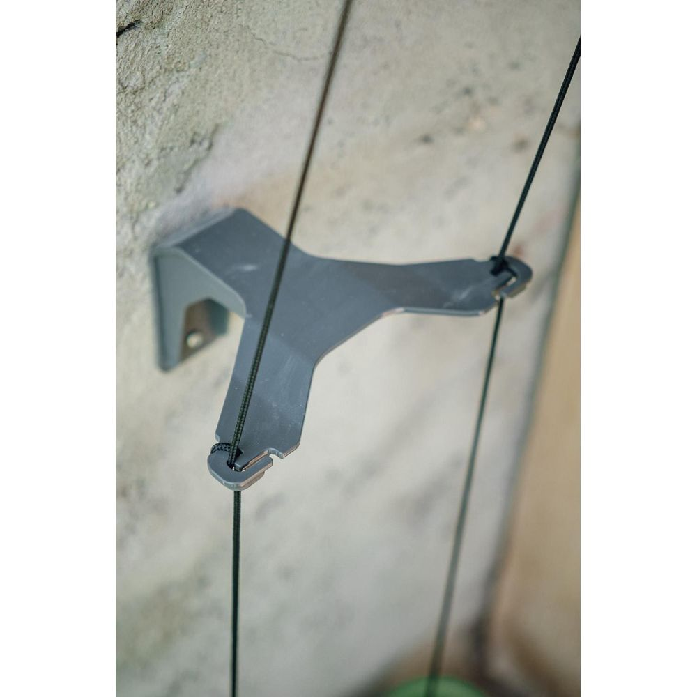 Ein grauer Metallhalter an einer Wand mit einem schwarzen Seil, das hindurchläuft.