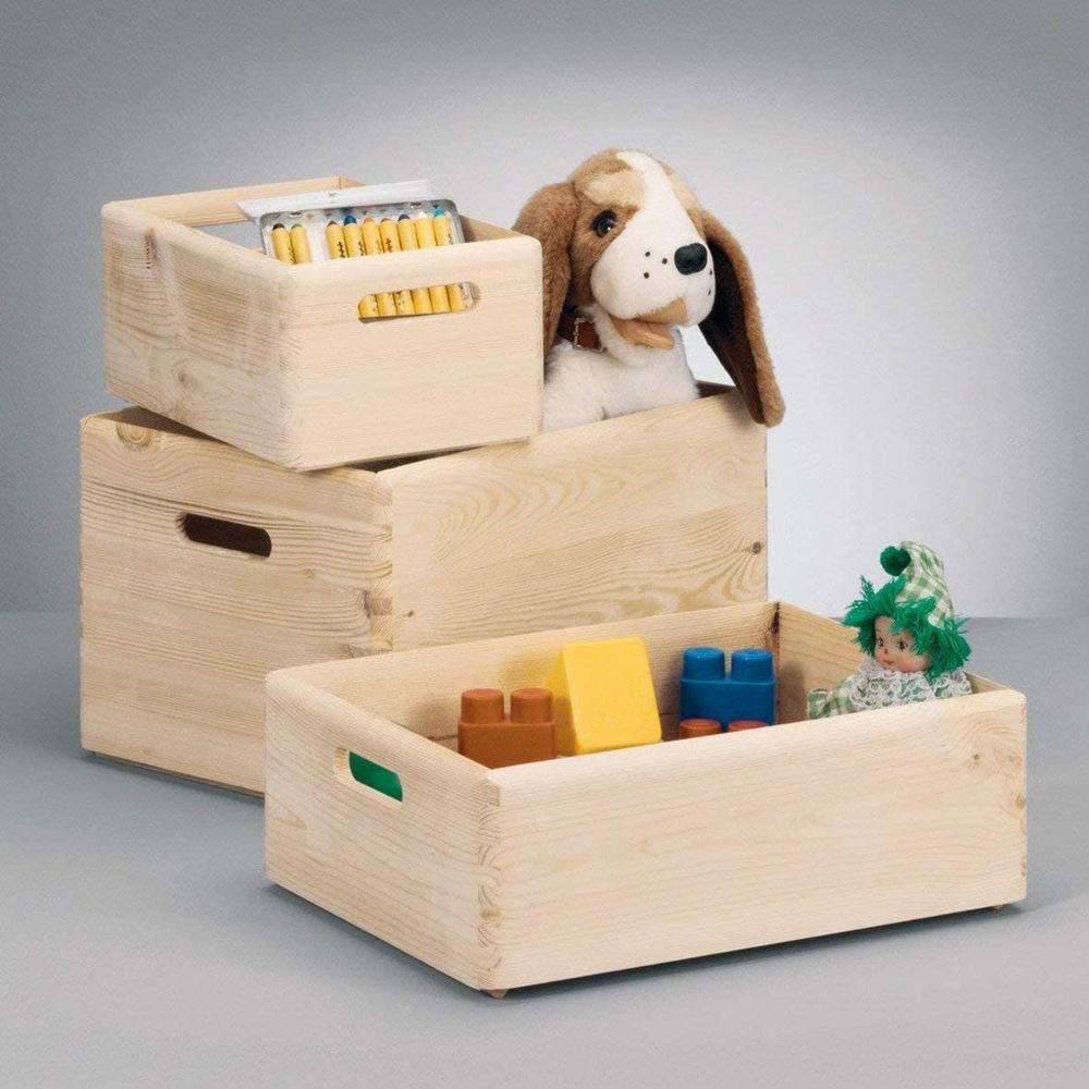 Drei Holzkisten mit Spielzeug und einem Plüschhund. Eine Kiste enthält Stifte. Blöcke, eine Puppe und ein Hundespielzeug sind sichtbar.