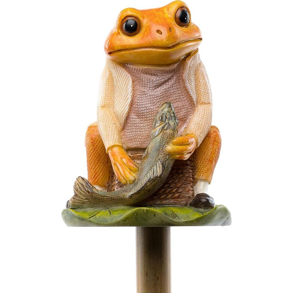 Orange Froschfigur sitzt mit Fisch auf einem Blatt, trägt eine Weste und Jacke.