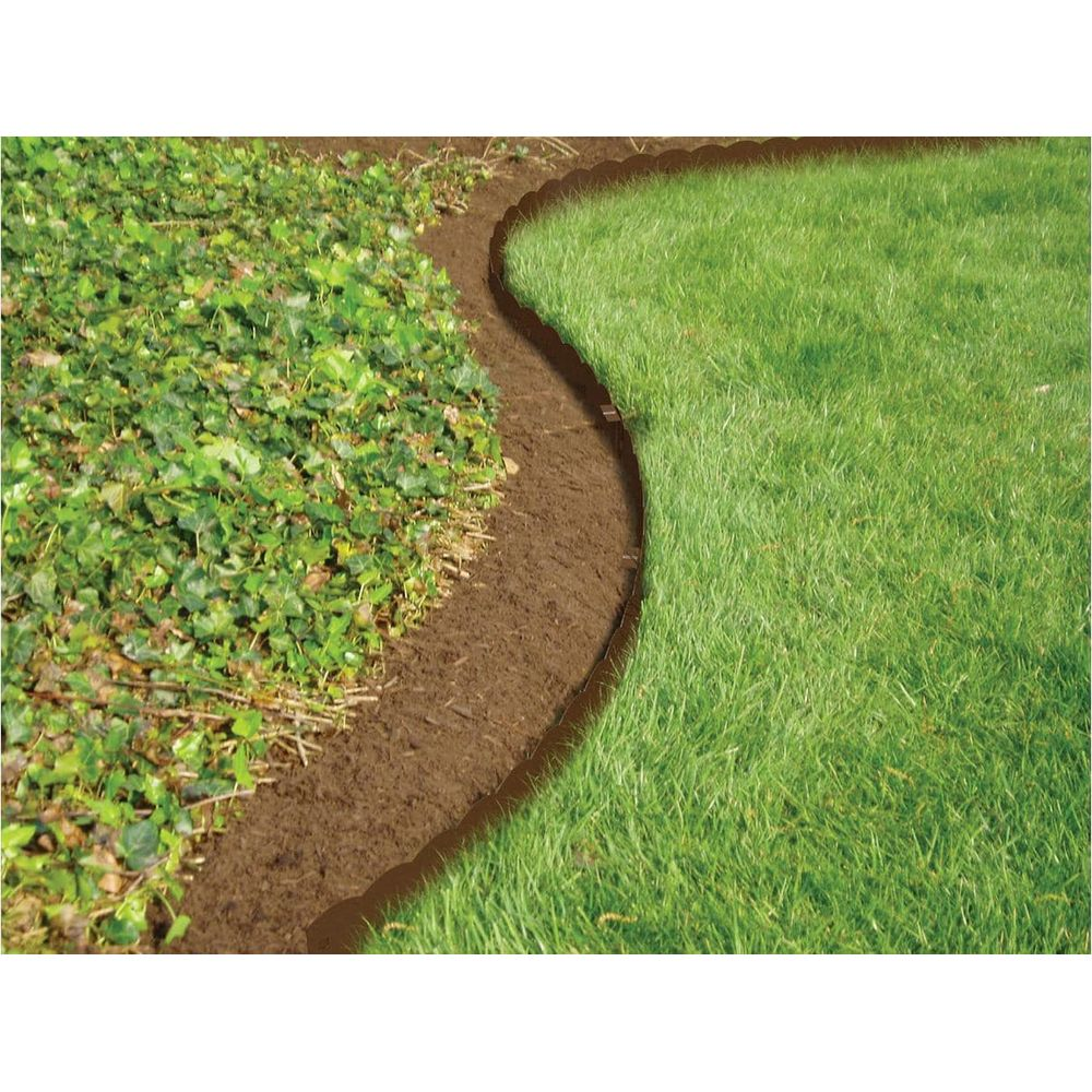 Eine geschwungene braune Kante trennt grünen Rasen von grüner Hecke.