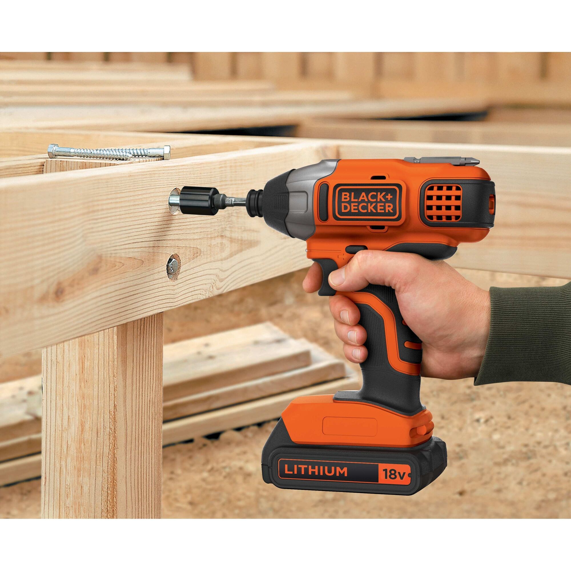 Mano tiene trapano arancione, avvitando una vite nel legno.