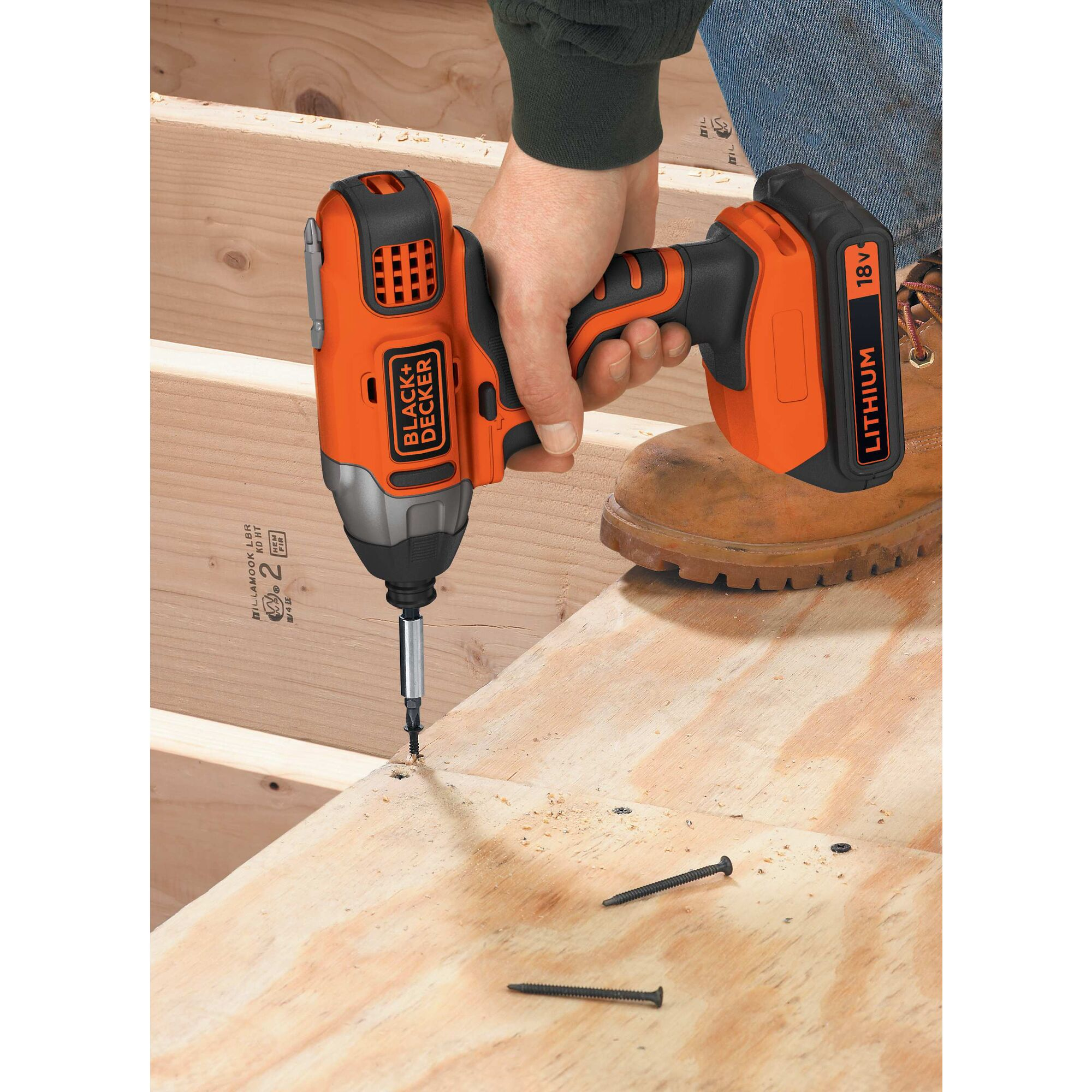Una persona usa un trapano Black+Decker arancione per avvitare nel legno. Due viti sono vicine.