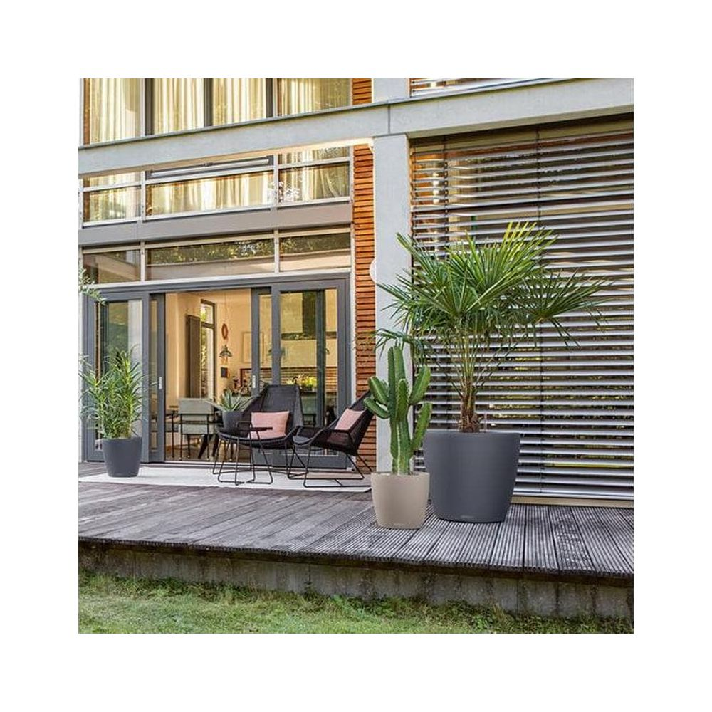 Ein moderner Sitzbereich im Freien mit Pflanzen und Möbeln vor einem Haus.