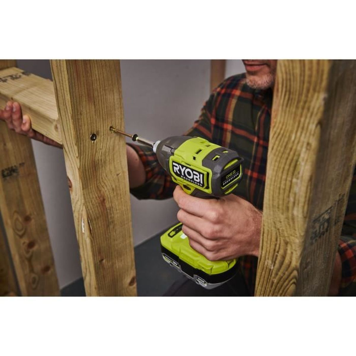 Mann schraubt mit gelber Ryobi Bohrmaschine in Holz.