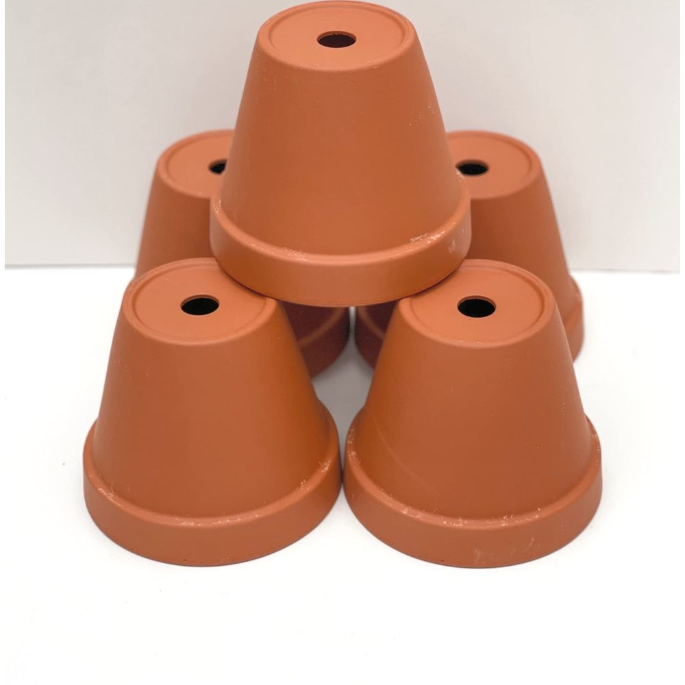 Cinq petits pots de fleurs en terre cuite sont empilés sur fond blanc.