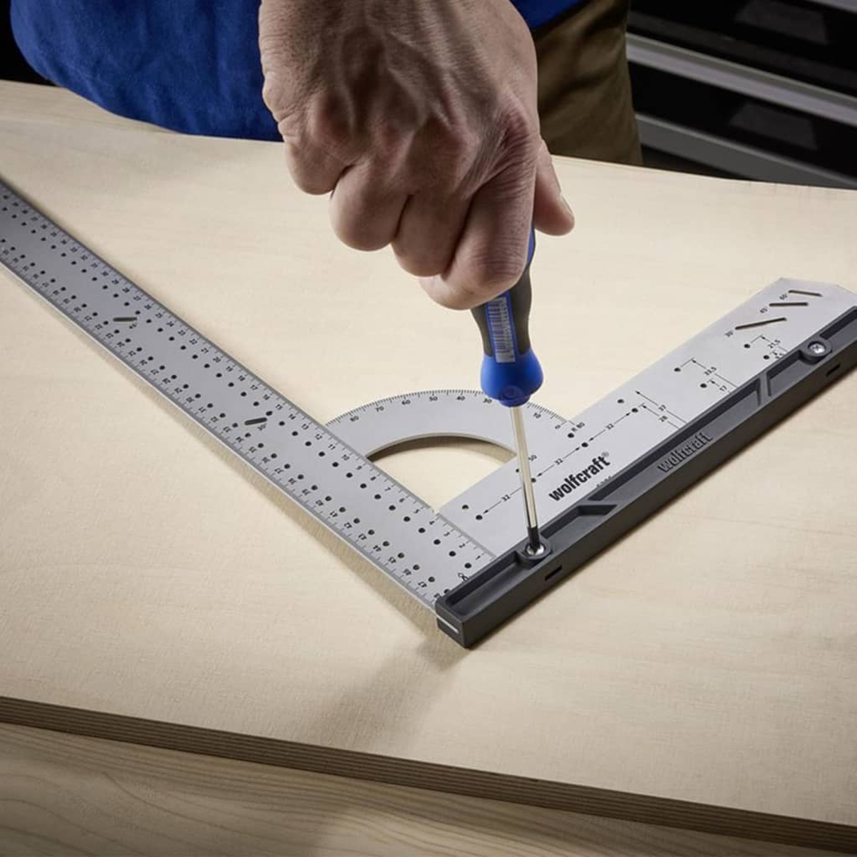 Eine Hand benutzt einen Schraubendreher, um ein Werkzeug auf Holz zu befestigen.