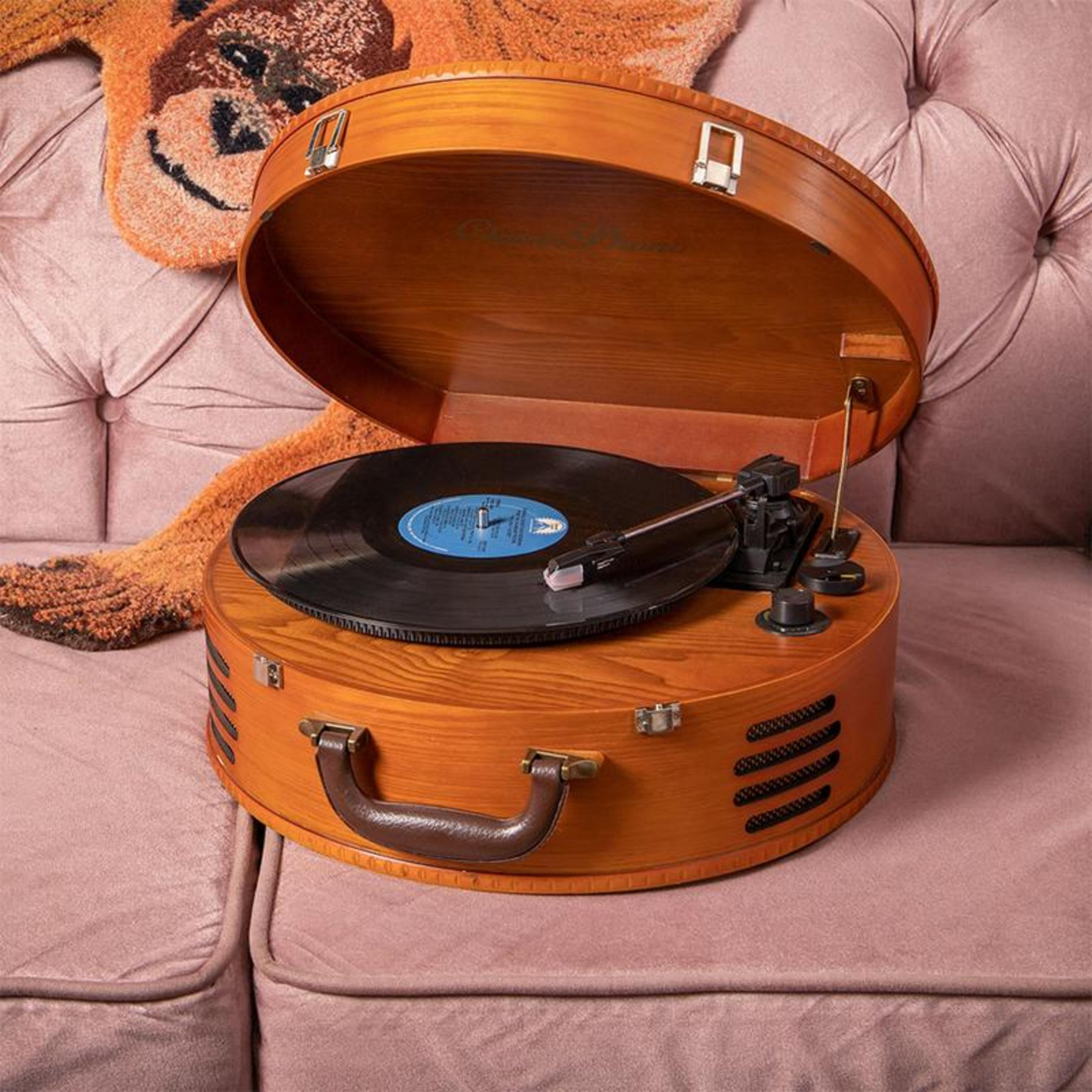 Pembe bir koltuk üzerinde vinil plaklı ahşap taşınabilir pikap.