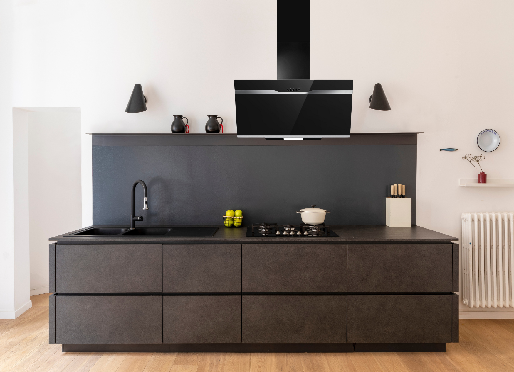 Moderne dunkelgraue Küche mit schwarzem Wasserhahn, Kochfeld und Dunstabzugshaube.