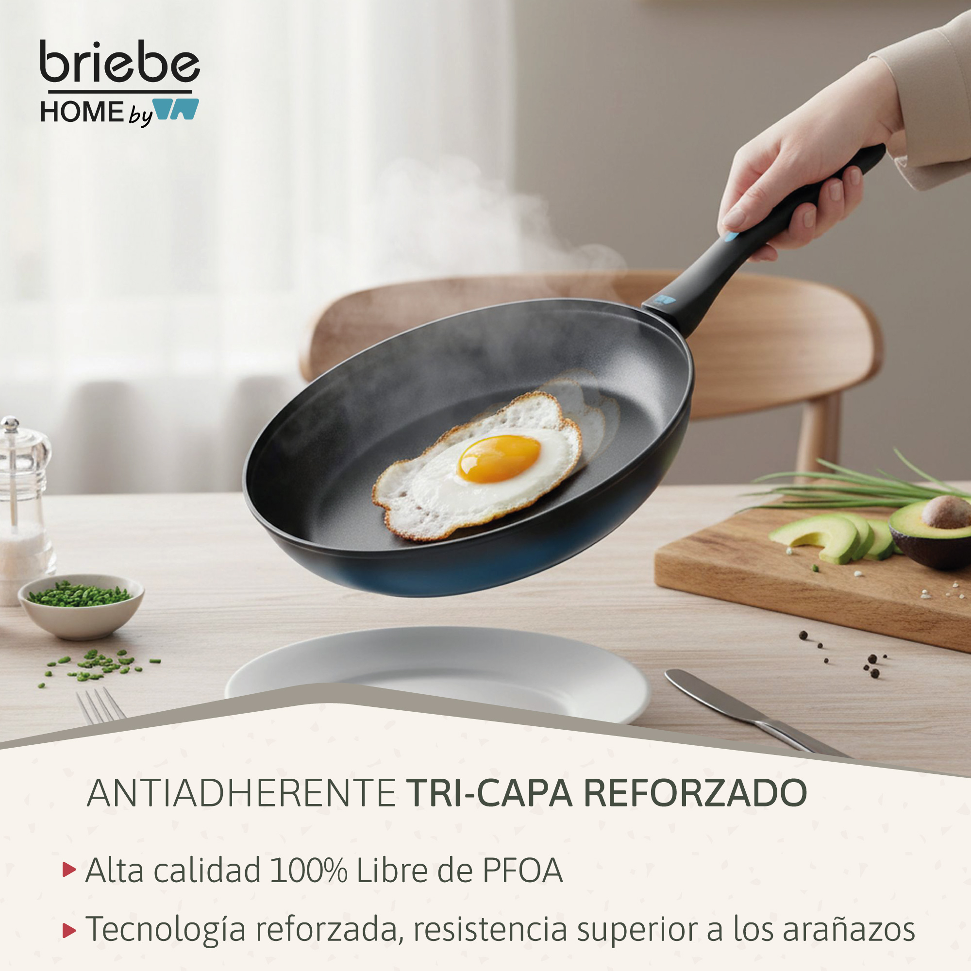 Una mano sostiene una sartén con un huevo frito. Cerca hay aguacate y hierbas.