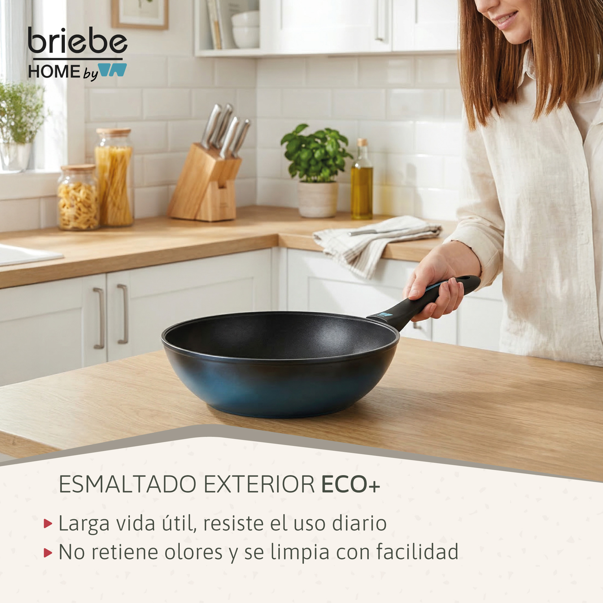Una mujer sostiene una sartén azul en una cocina con pasta y cuchillos.