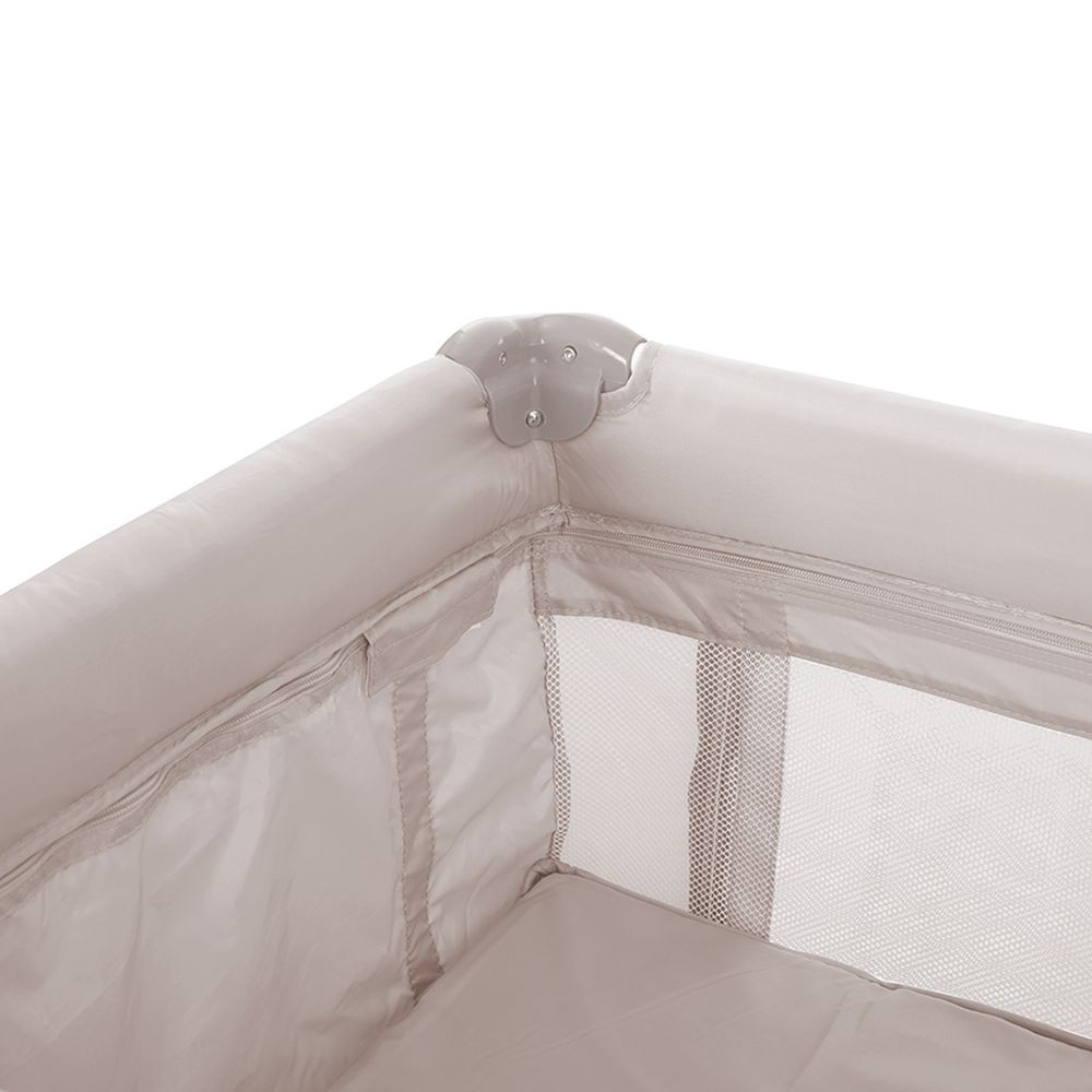 Nahaufnahme einer beige faltbaren Babywiege mit Reißverschluss und Netzfenstern.