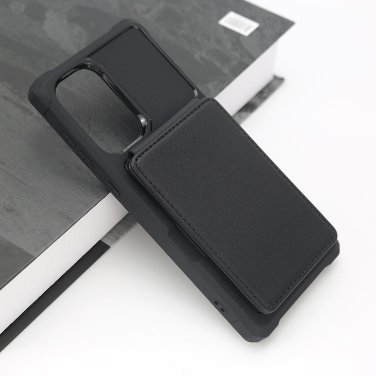 Custodia nera per telefono con porta carte in pelle su un libro.