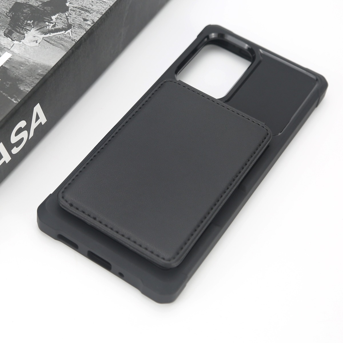 Custodia nera per telefono con porta carte su un libro.