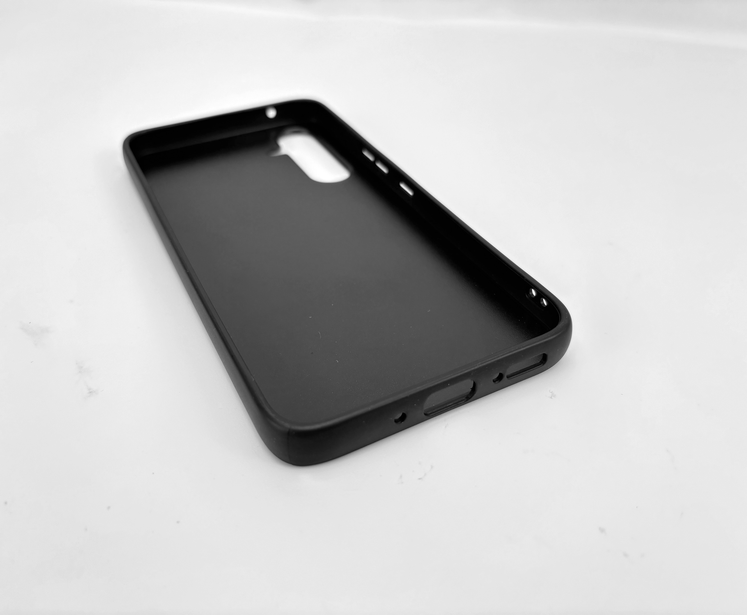 Custodia nera per telefono con ritagli per fotocamera e porte, su sfondo bianco.