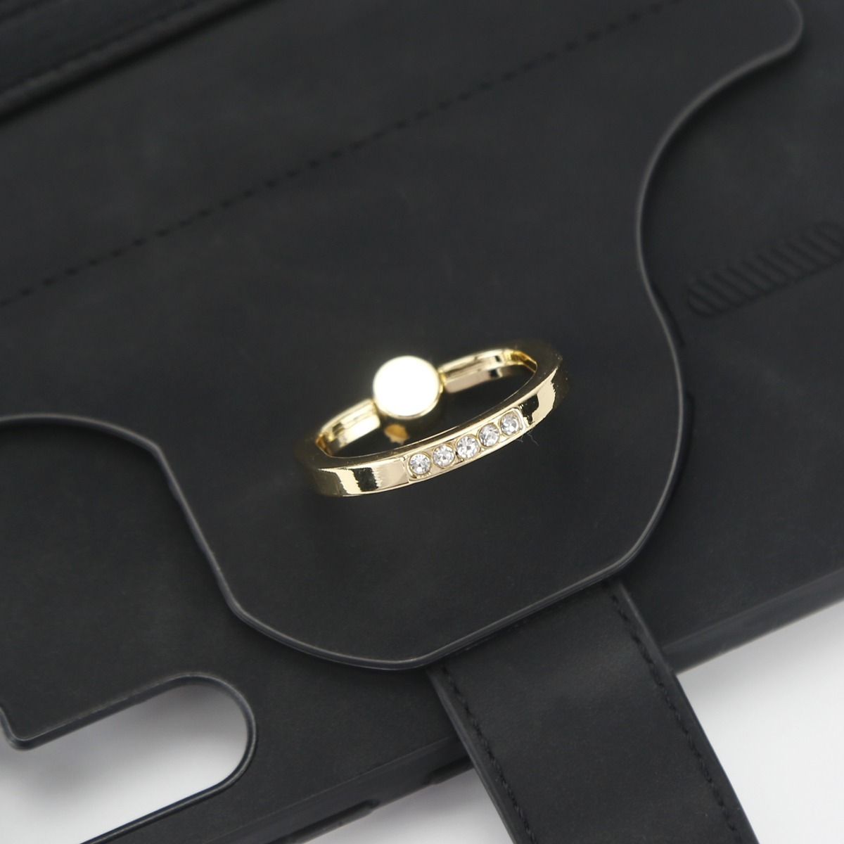 Goldener Handyhalter mit Strasssteinen auf schwarzem Leder.