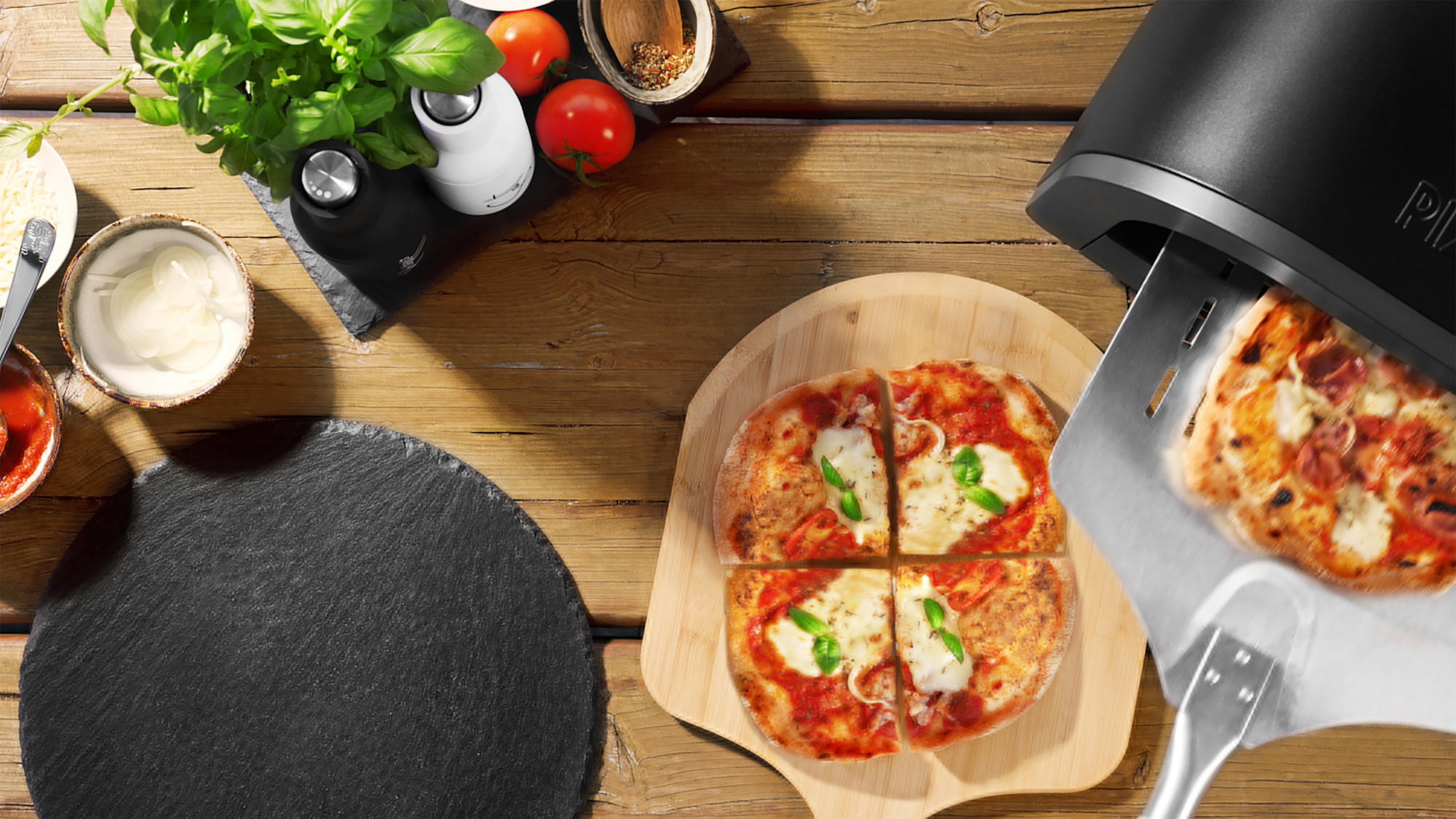 Un four à pizza avec une pizza sur une pelle et une autre pizza sur une planche en bois.