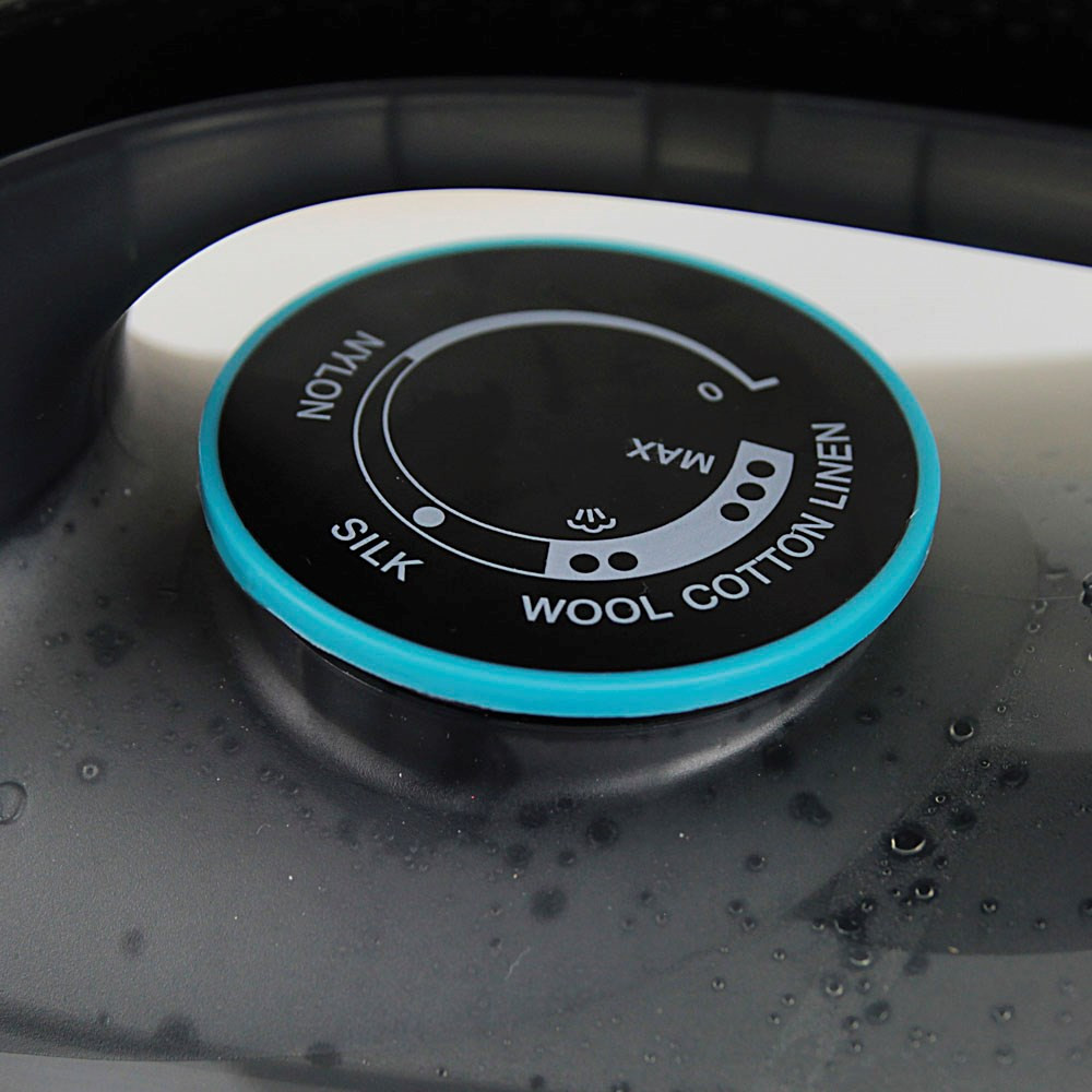 Zbliżenie pokrętła ustawień tkaniny żelazka, pokazujące jedwab, wełnę, bawełnę, len.