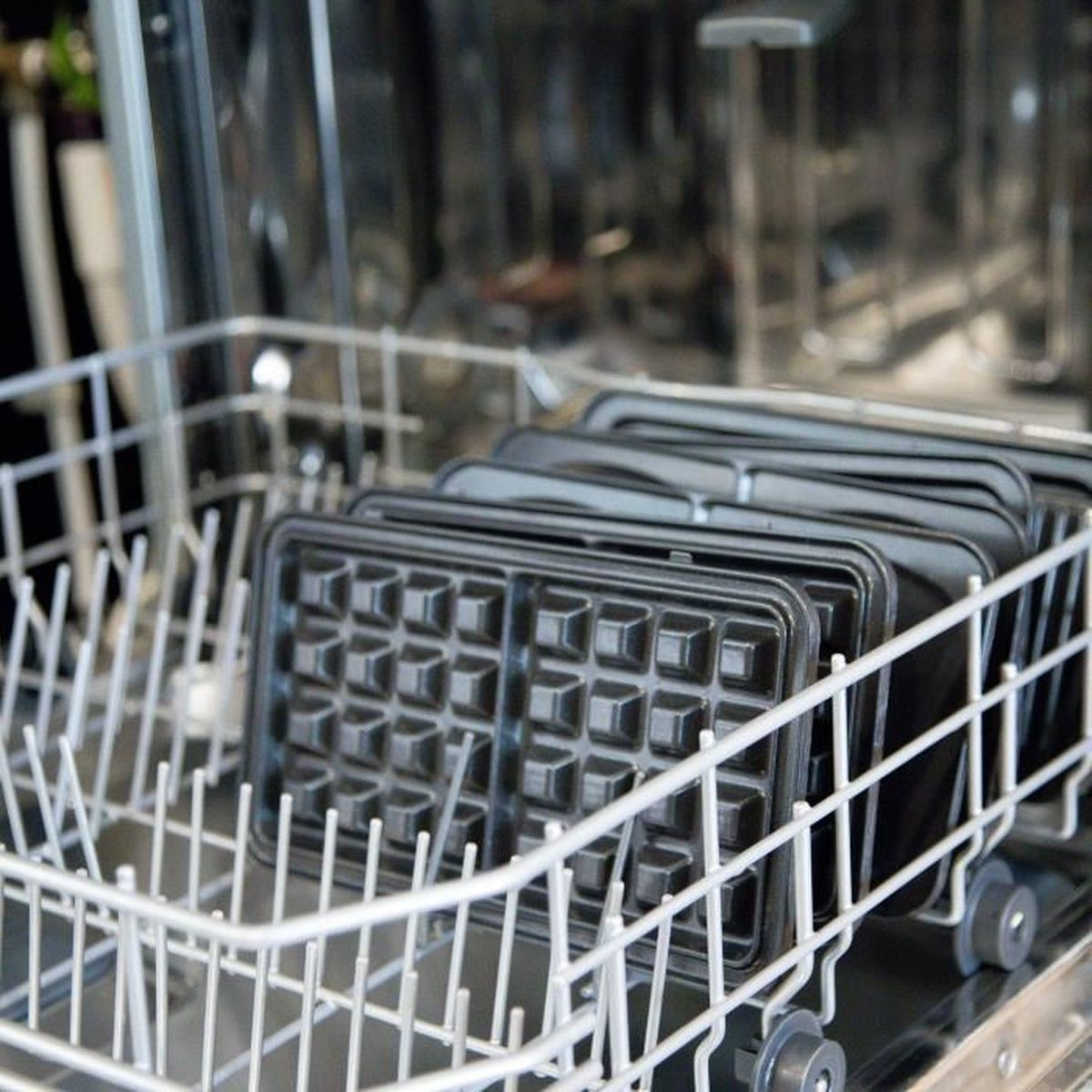Muffole per waffle impilati dentro un cestello per lavastoviglie.