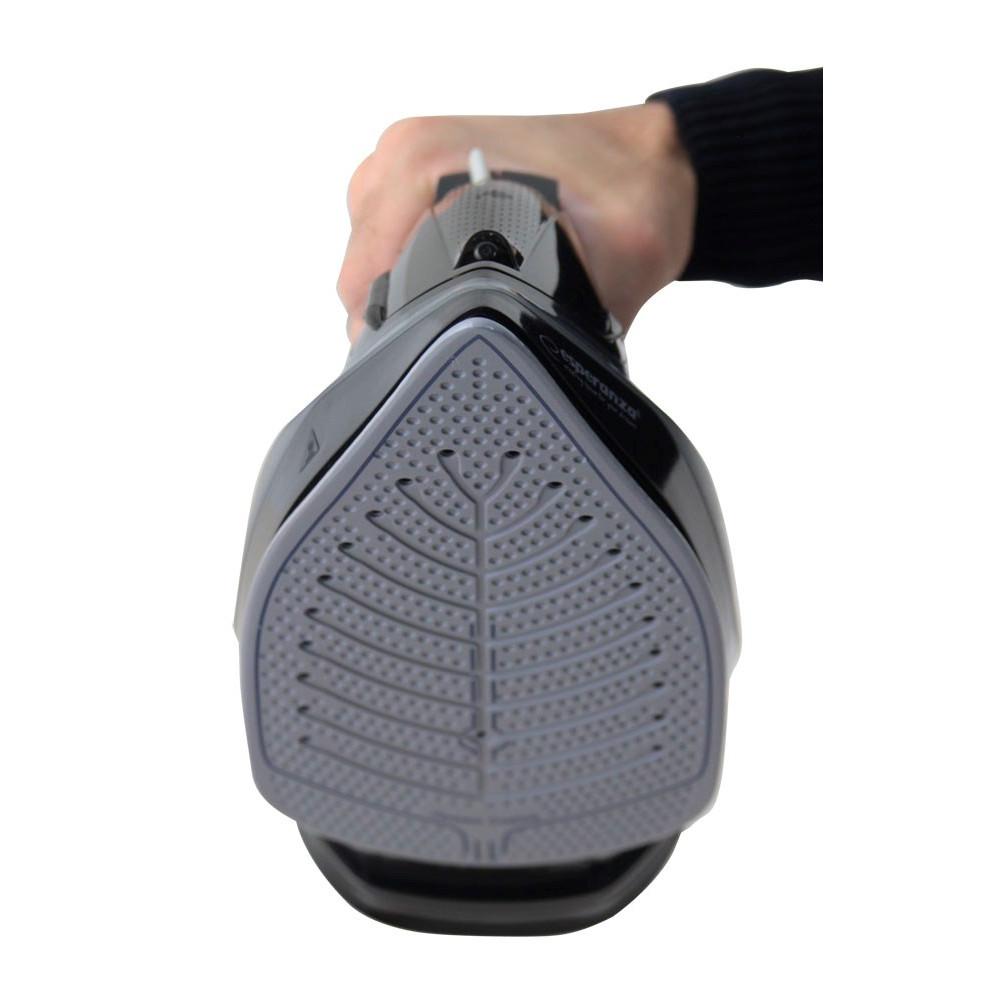 Dłoń trzyma czarne żelazko, zbliżenie na stopę z otworami parowymi.