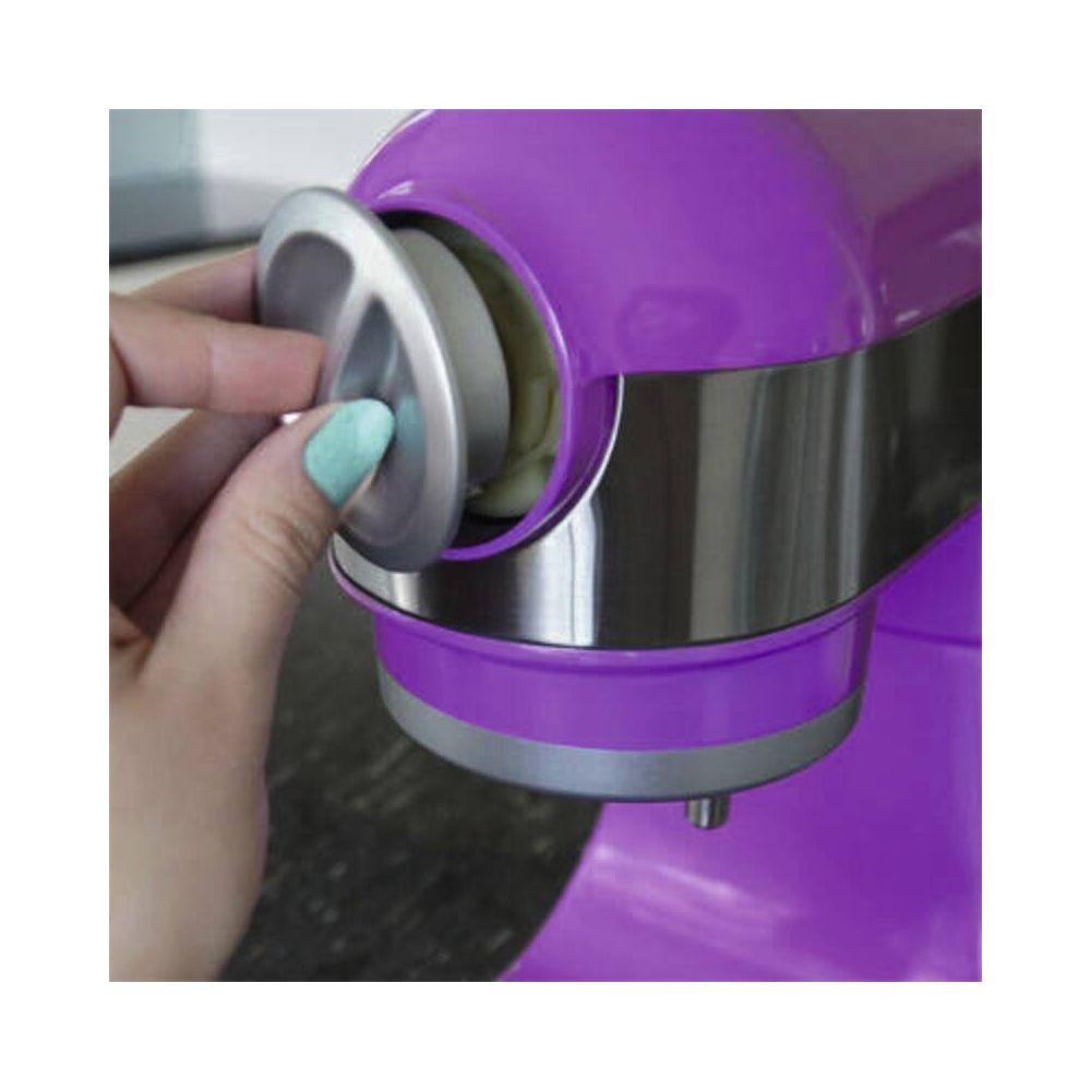 Una mano con unghie verde menta rimuove un tappo argentato da un elettrodomestico viola.