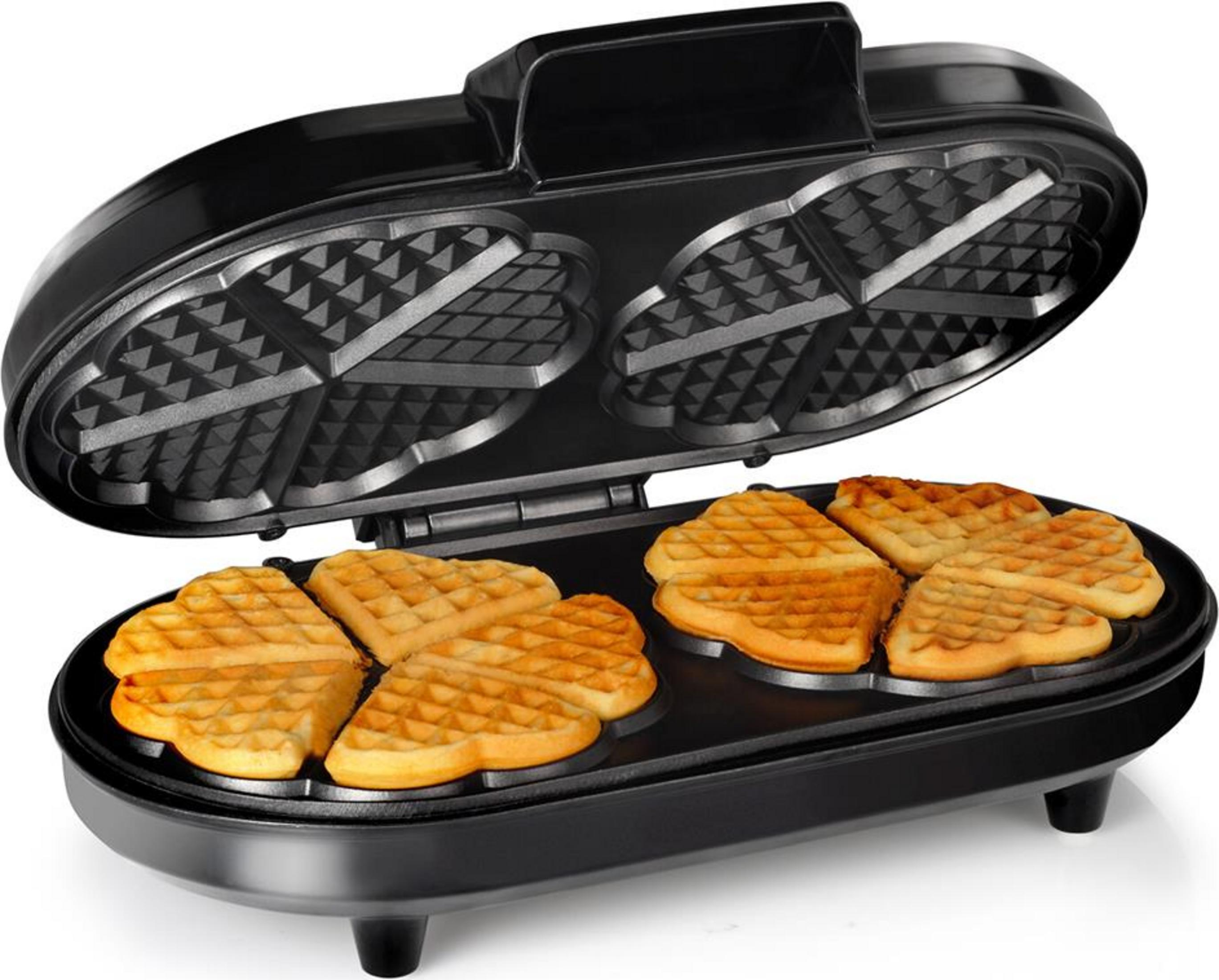 Un gaufrier noir ouvert avec des gaufres en forme de cœur.