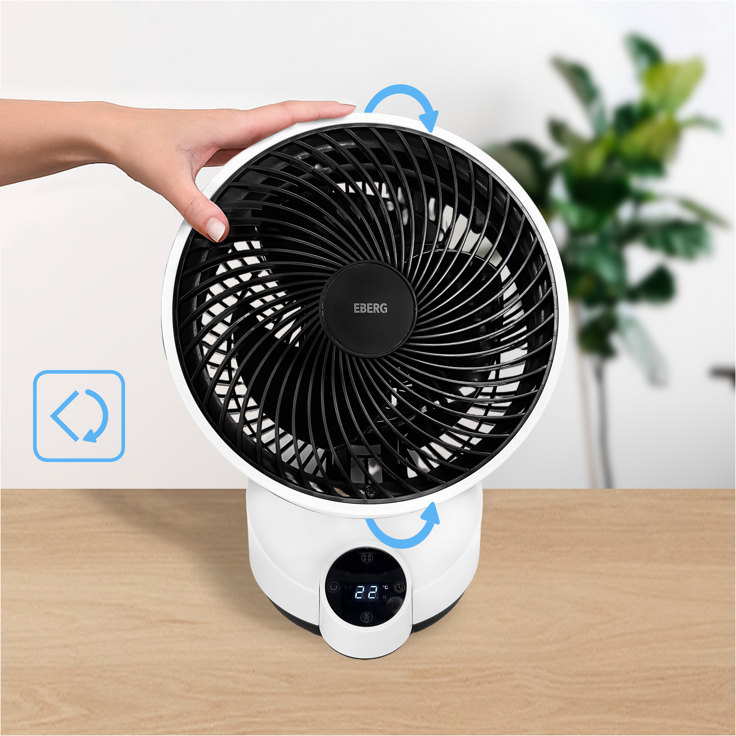 Biały wentylator z czarną kratką stoi na drewnianym stole.