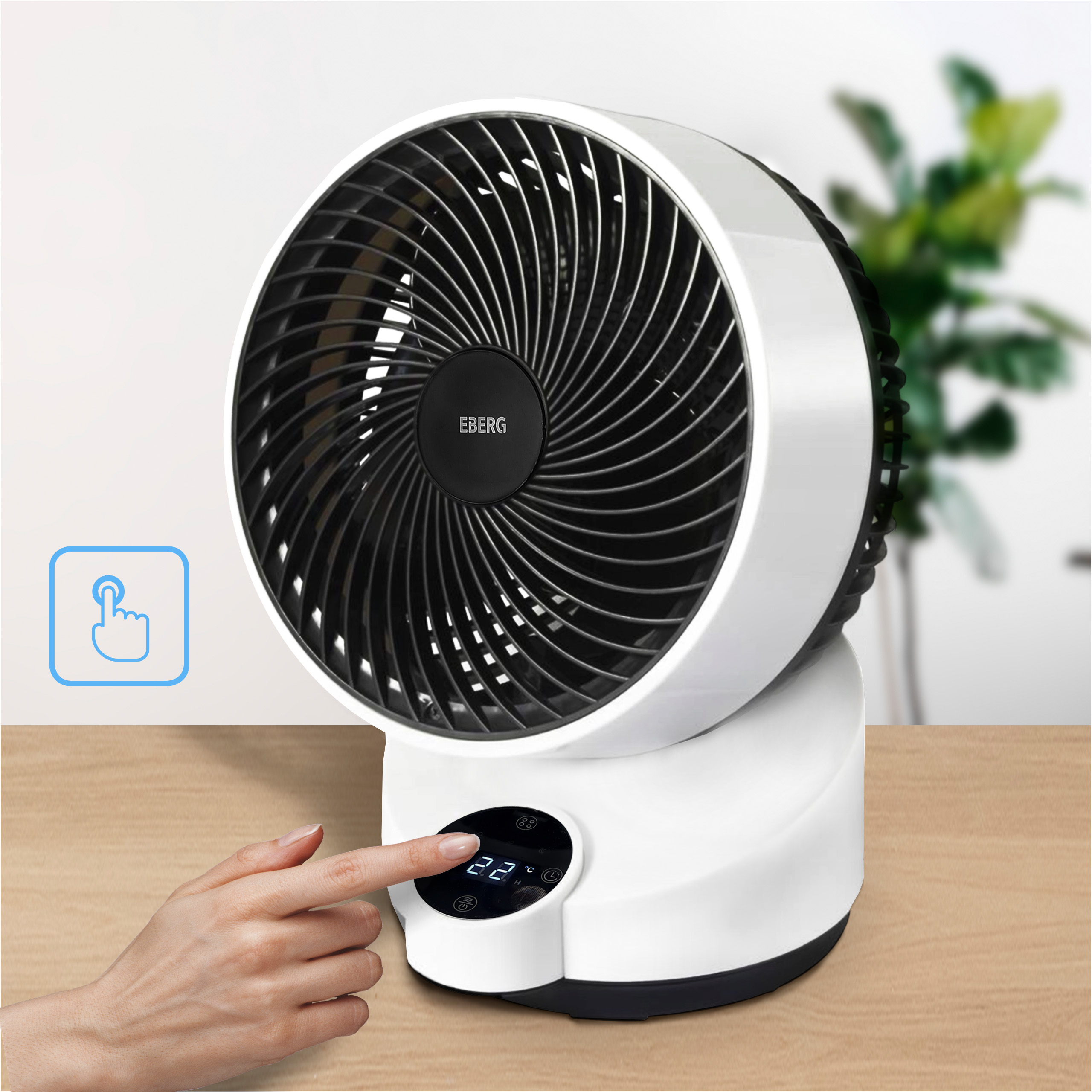Biały wentylator z czarną kratką stoi na drewnianym stole. Ręka dotyka wyświetlacza.
