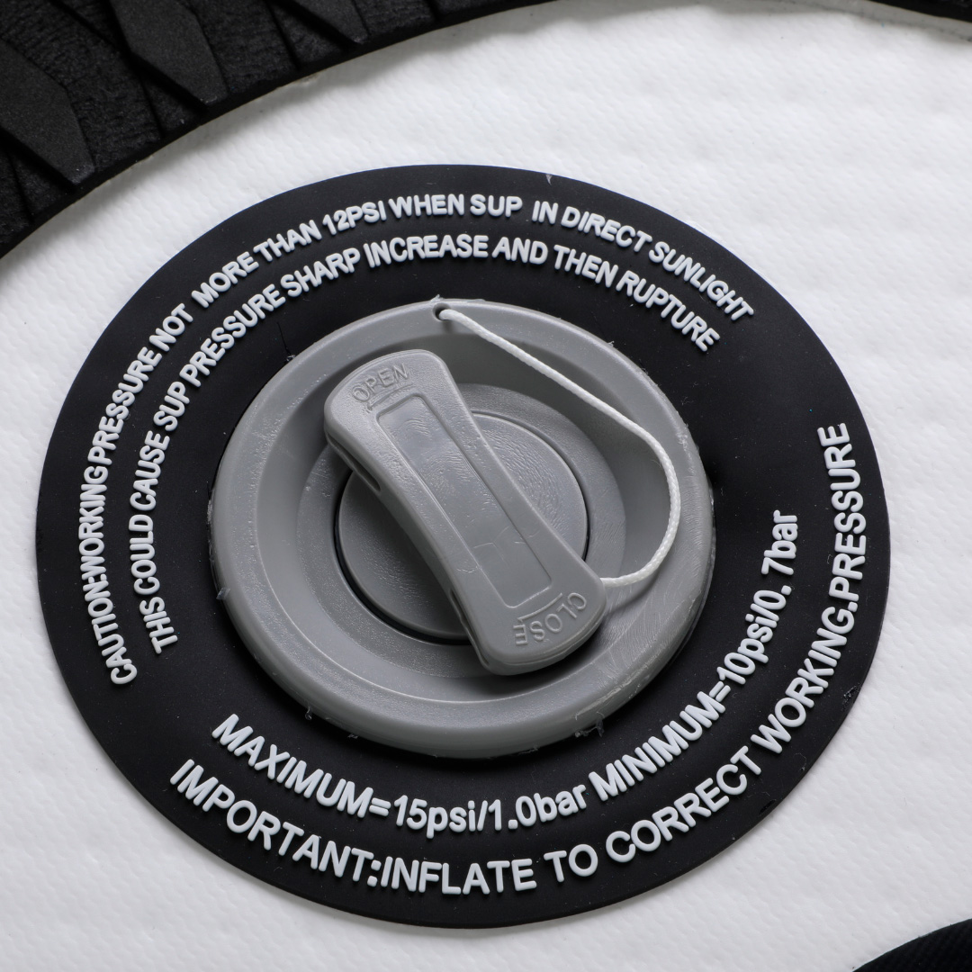 Primer plano de una válvula inflable gris sobre superficie blanca con advertencias de texto negro.