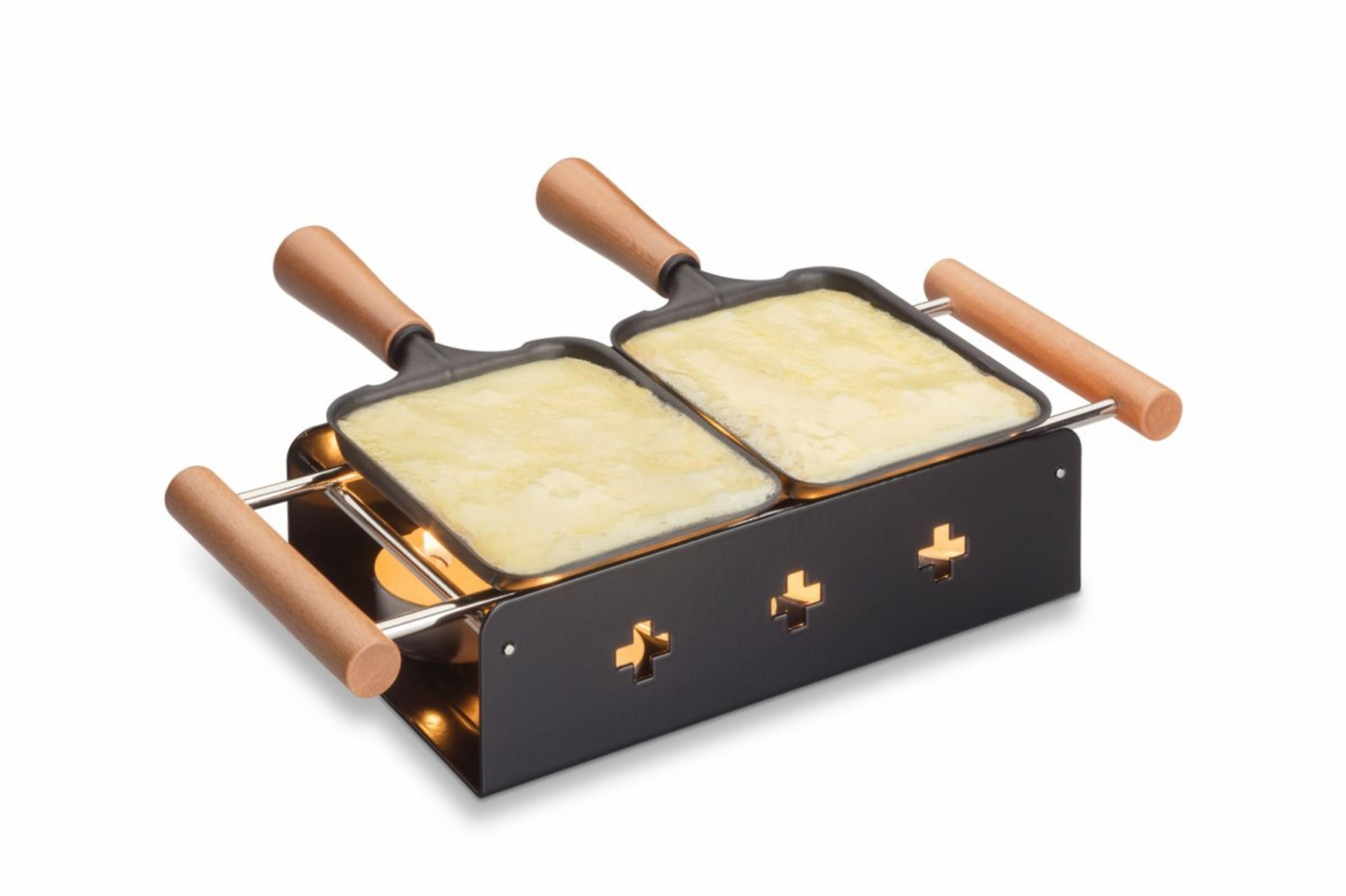 Una griglia per raclette con due padelle su scaldavivande a candela, sfondo bianco