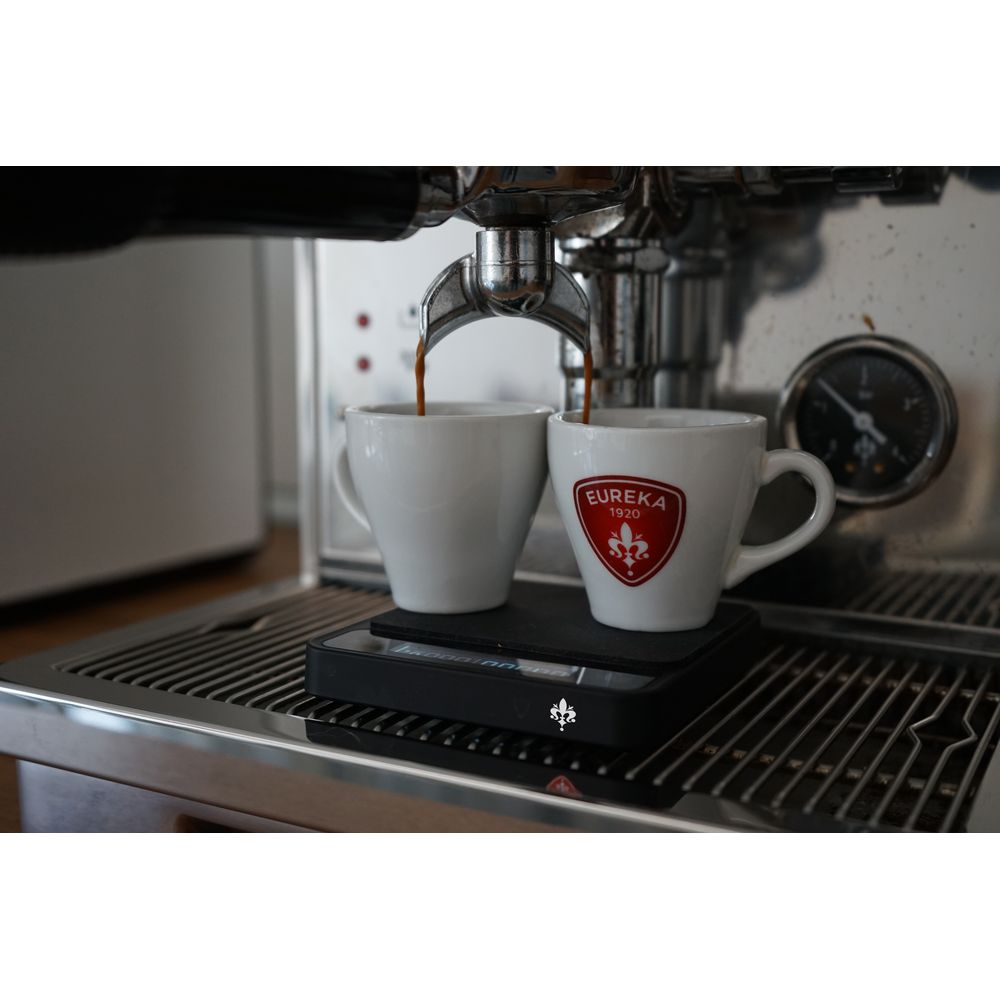Deux tasses à expresso sont remplies d'expresso fraîchement moulu sous une machine à café.