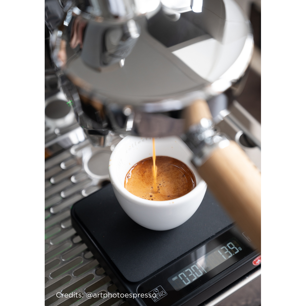 Espresso coulant dans une tasse blanche sur une balance noire.