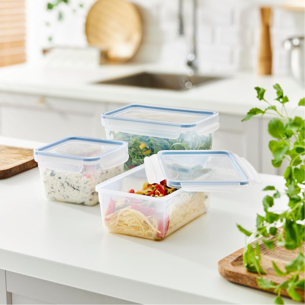 Contenitori per alimenti con coperchi blu, pieni di pasta, insalata e riso.