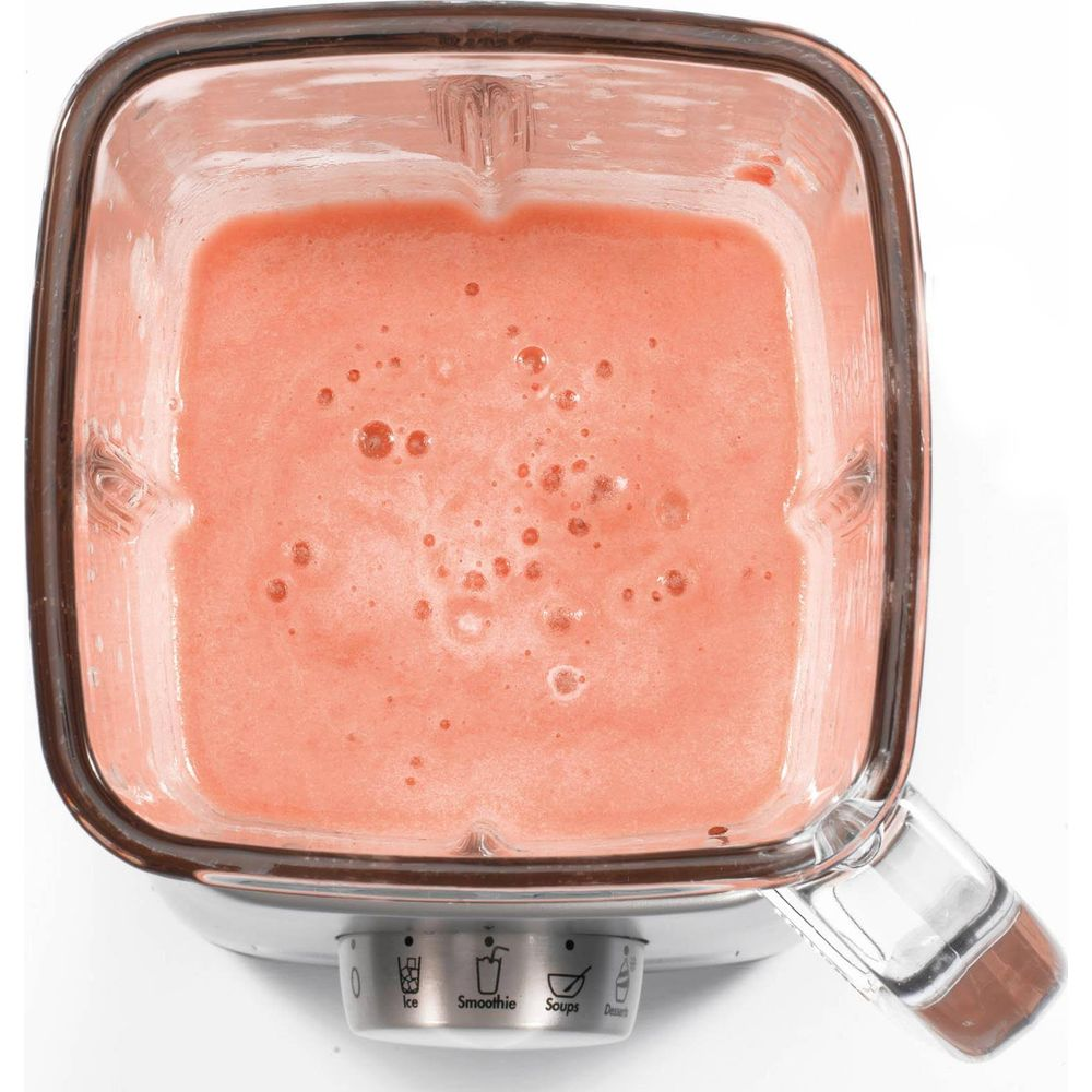Ein Mixerbehälter mit rosa-rotem Smoothie, gefüllt bis zur Hälfte.