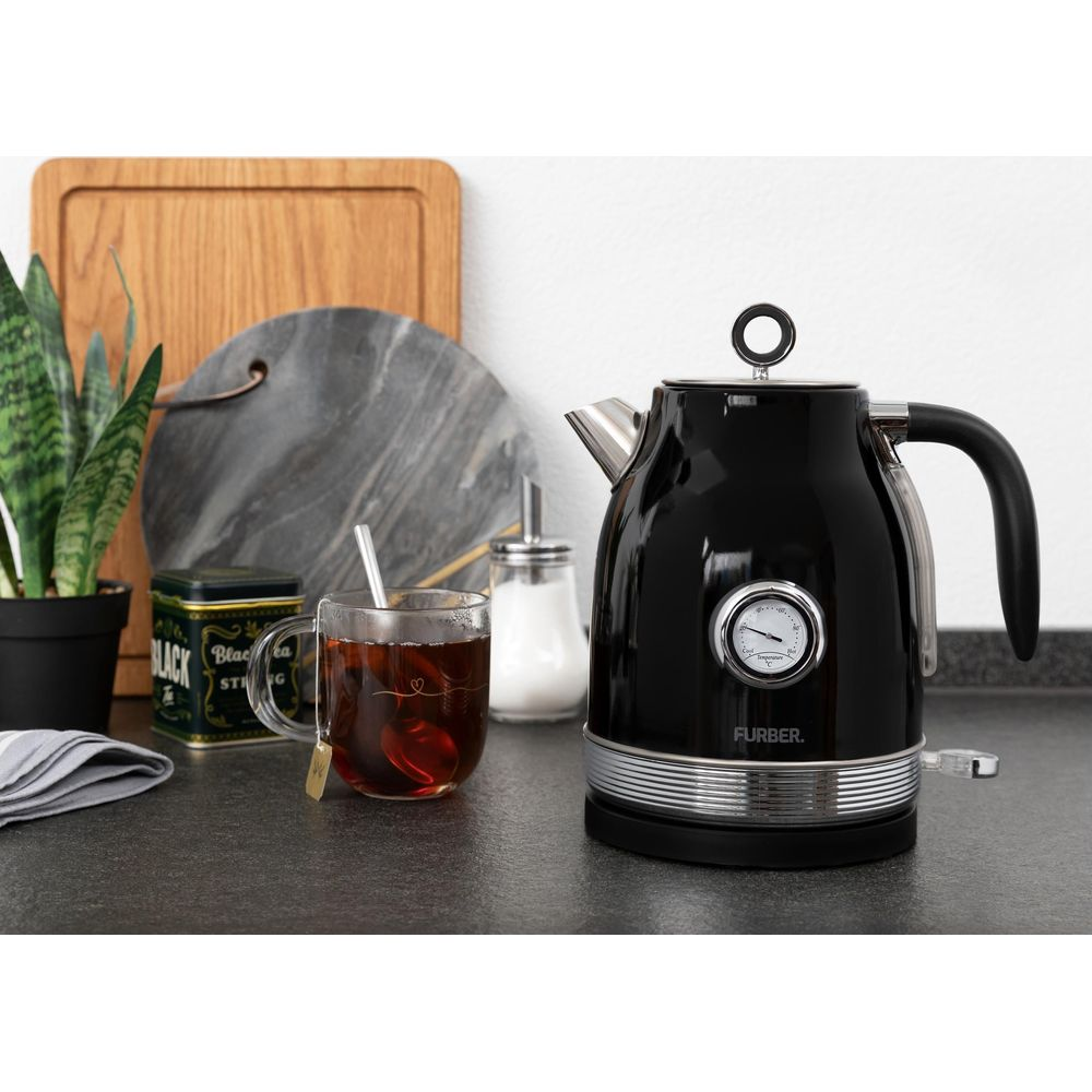 Schwarzer Wasserkocher mit Temperaturanzeige, neben einer Teetasse und Zuckerdose.