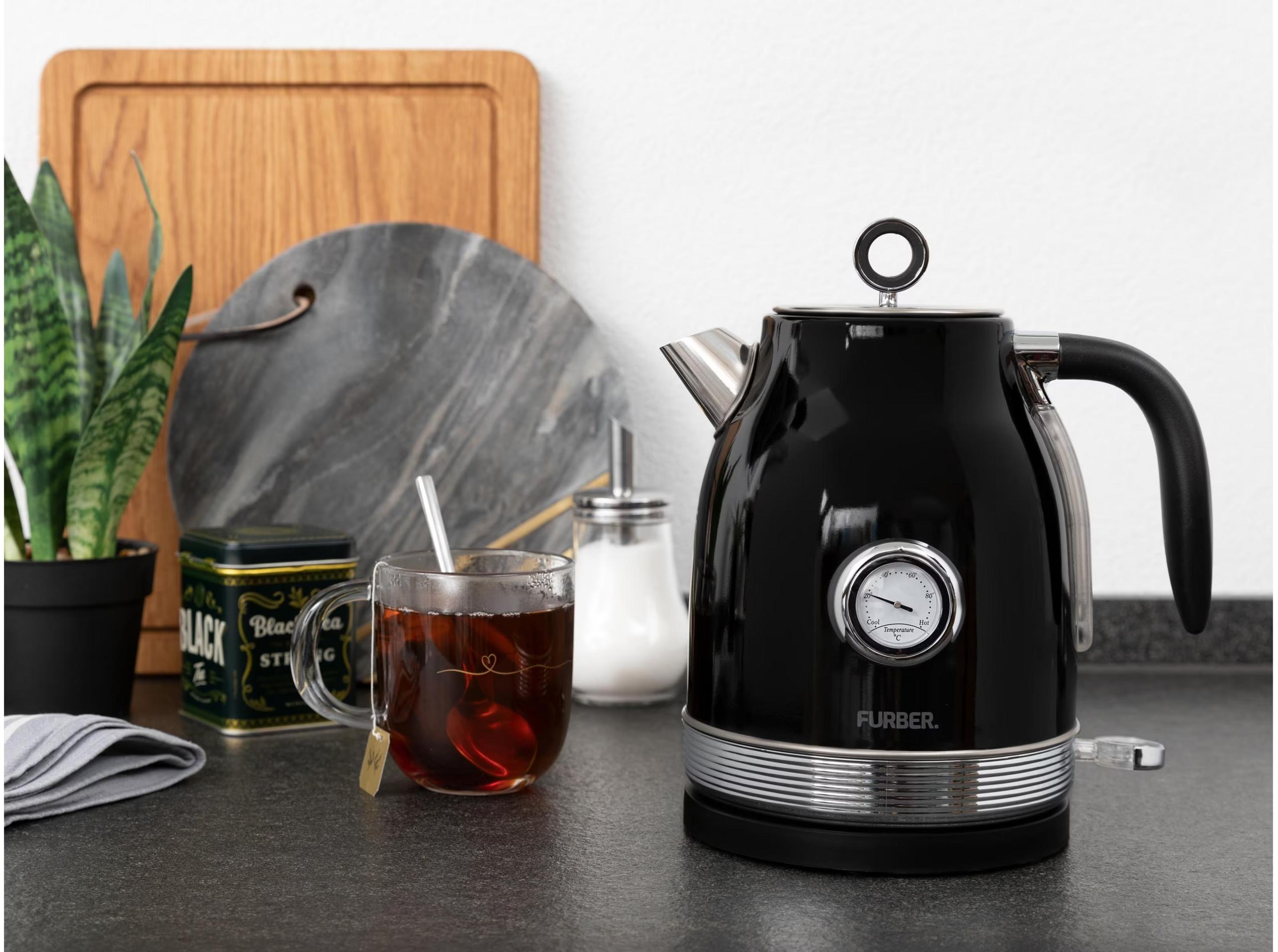 Schwarzer Wasserkocher mit Temperaturanzeige neben einer Tasse Tee.
