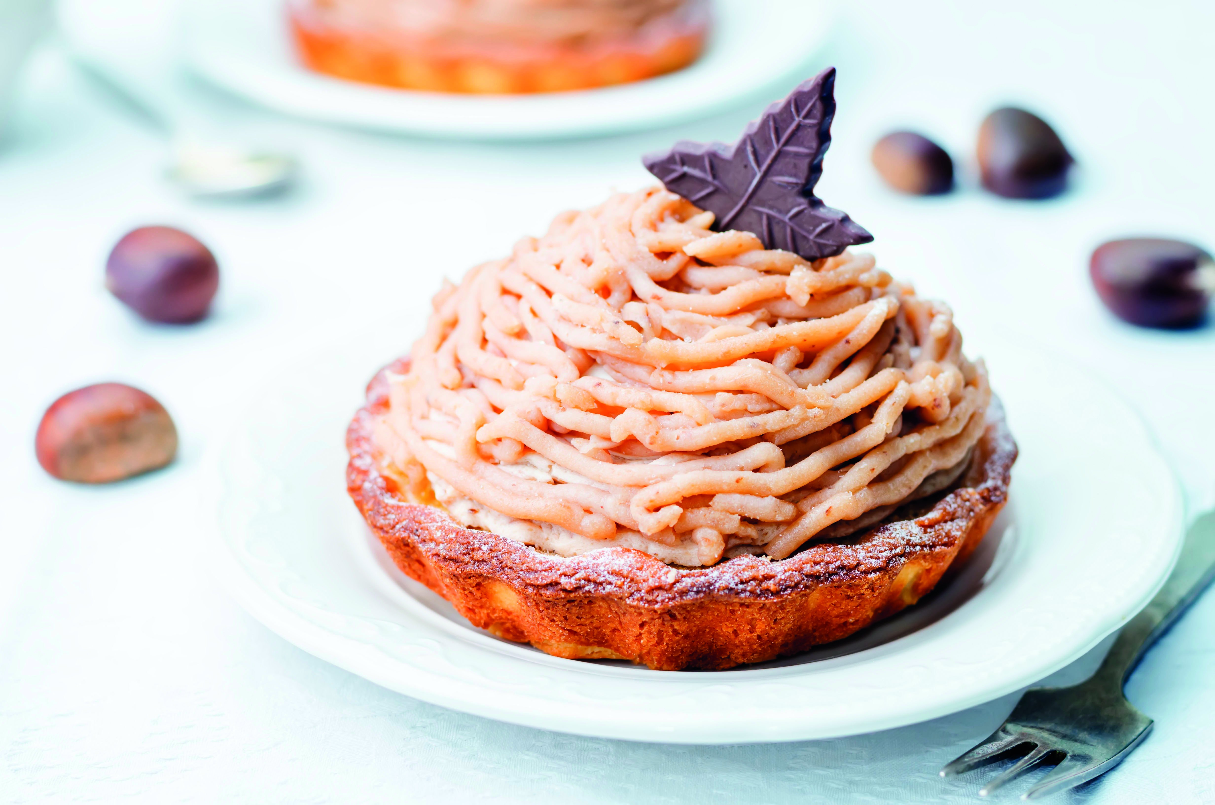 Gâteau aux marrons avec crème et feuille de chocolat sur une assiette.