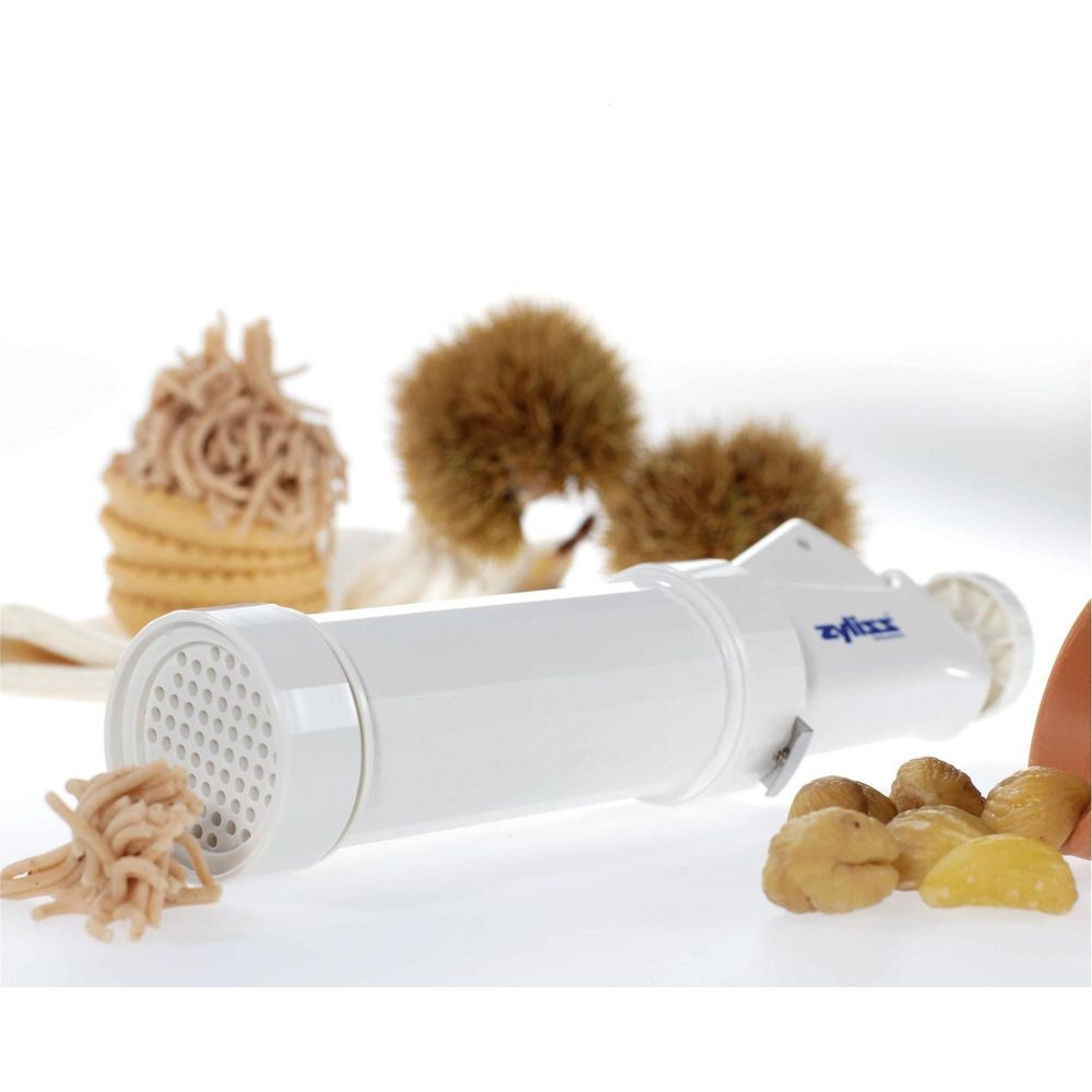 Une machine à pâtes blanche extrude des spaghettis à côté de châtaignes et de pâtes cuites.