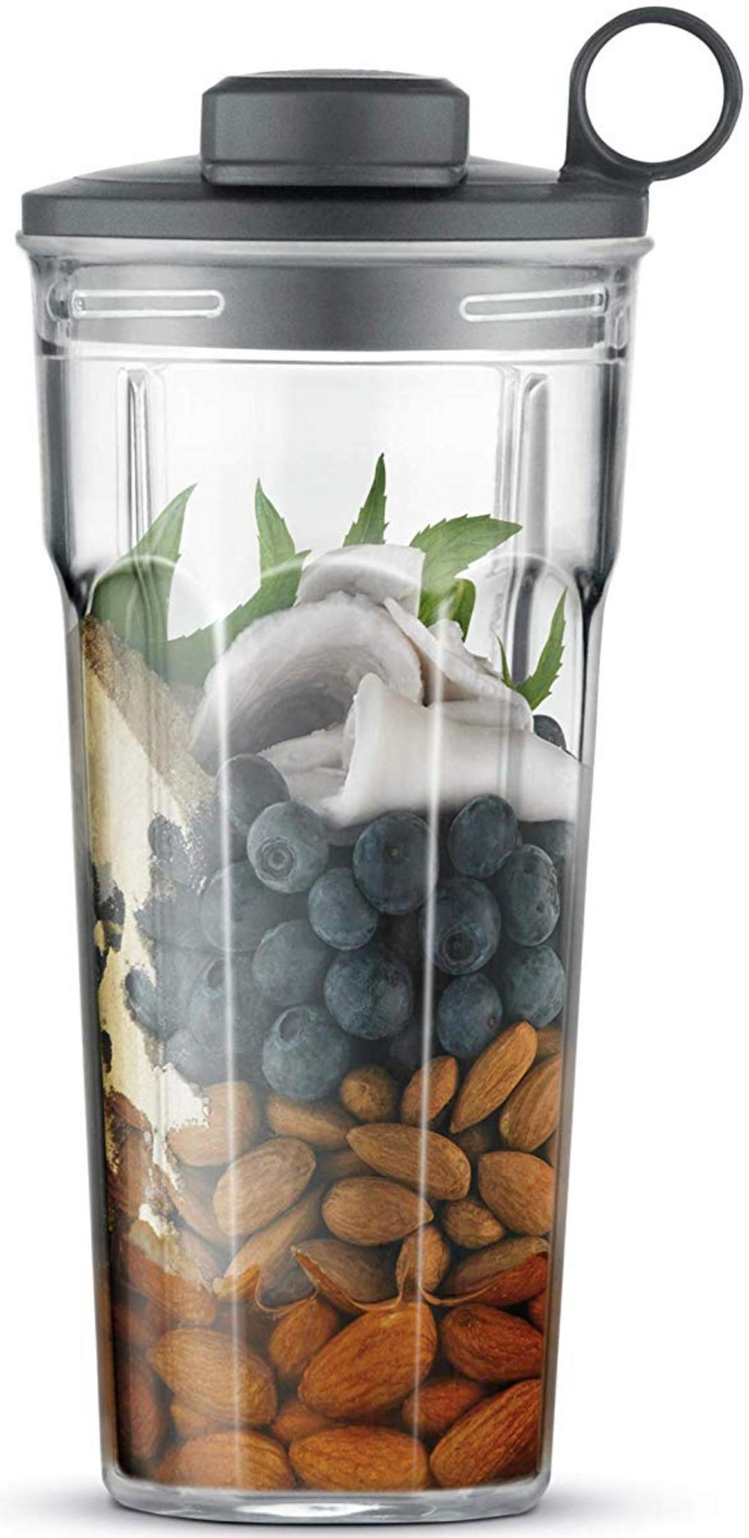 Un bicchiere del frullatore con mandorle, mirtilli, cocco e foglie di menta.