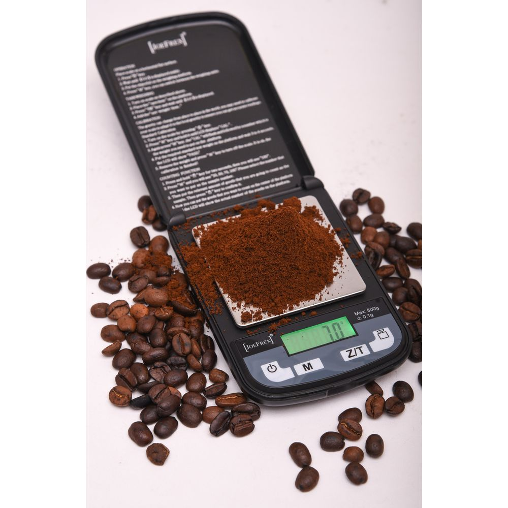 Une balance numérique avec poudre et grains de café.