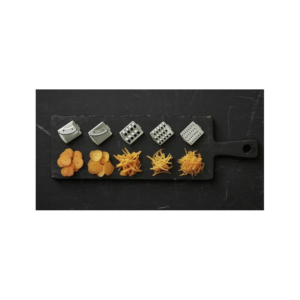 Cinq râpes et diverses carottes et pommes de terre coupées sur une planche.